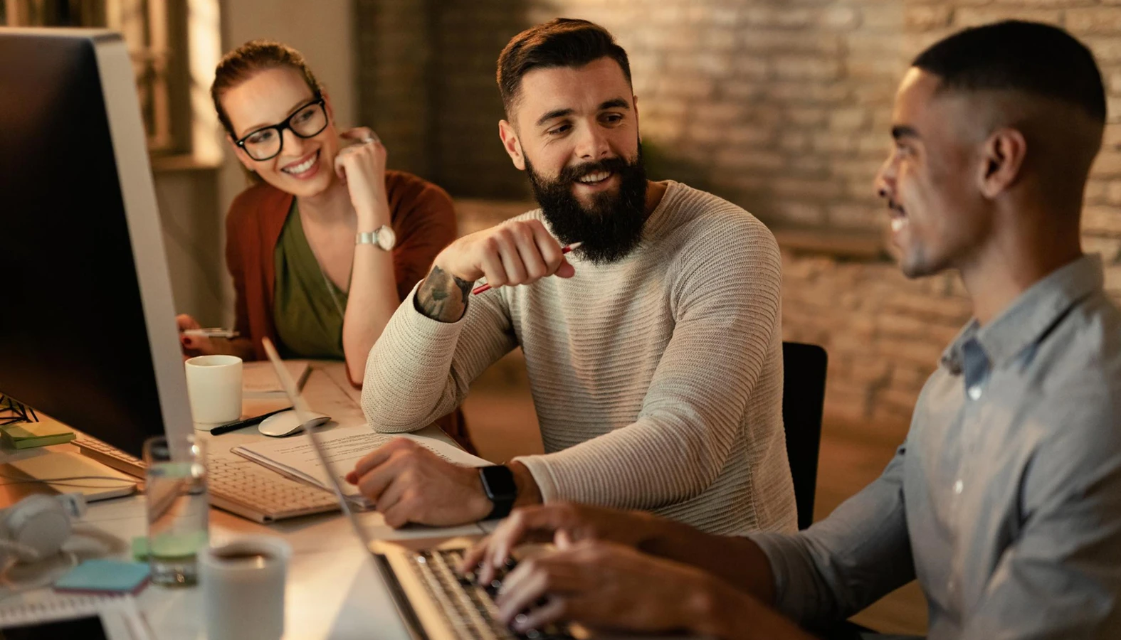 Young entrepreneurs working late in an office, with focus on a man with a beard