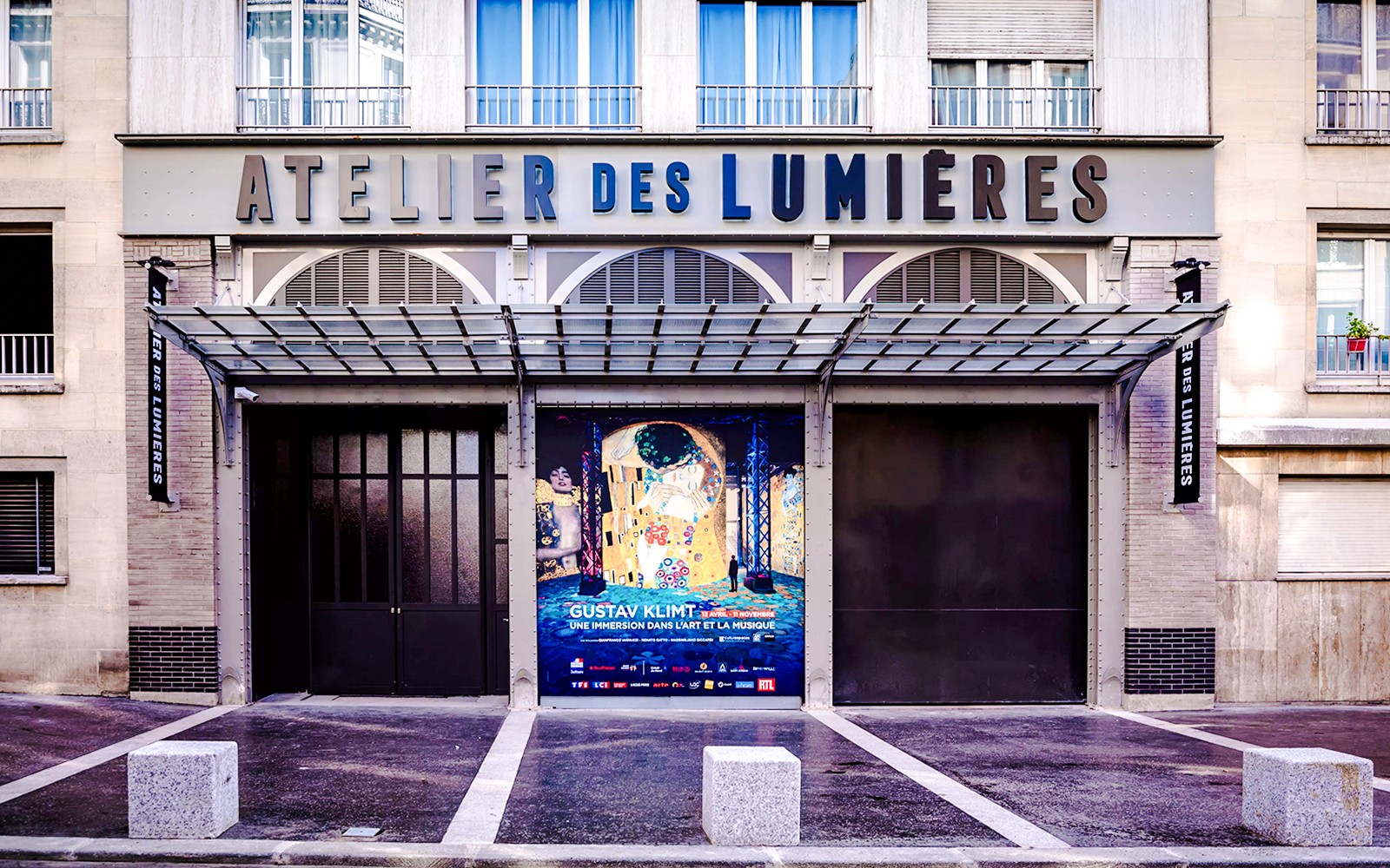 Exterior of Atelier Des Lumières in Paris with Gustav Klimt exhibition poster.