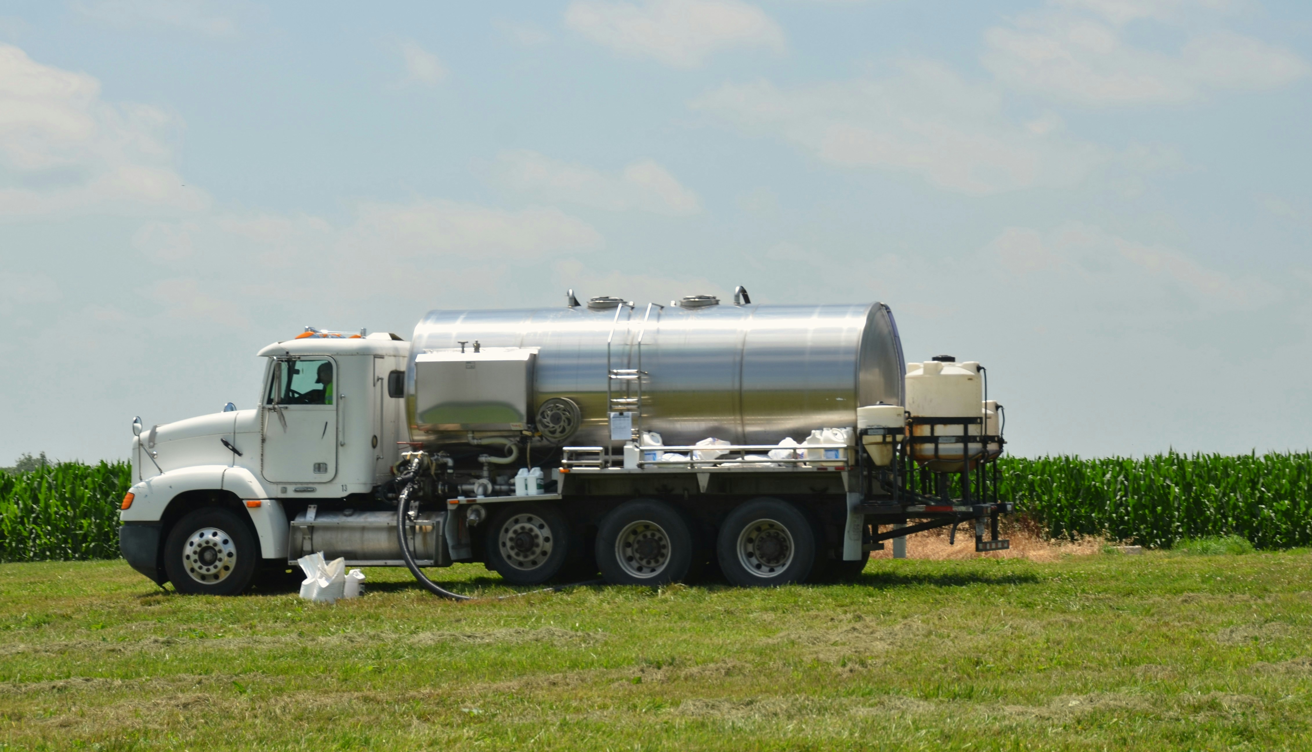 White tanker truck spraying water across a field