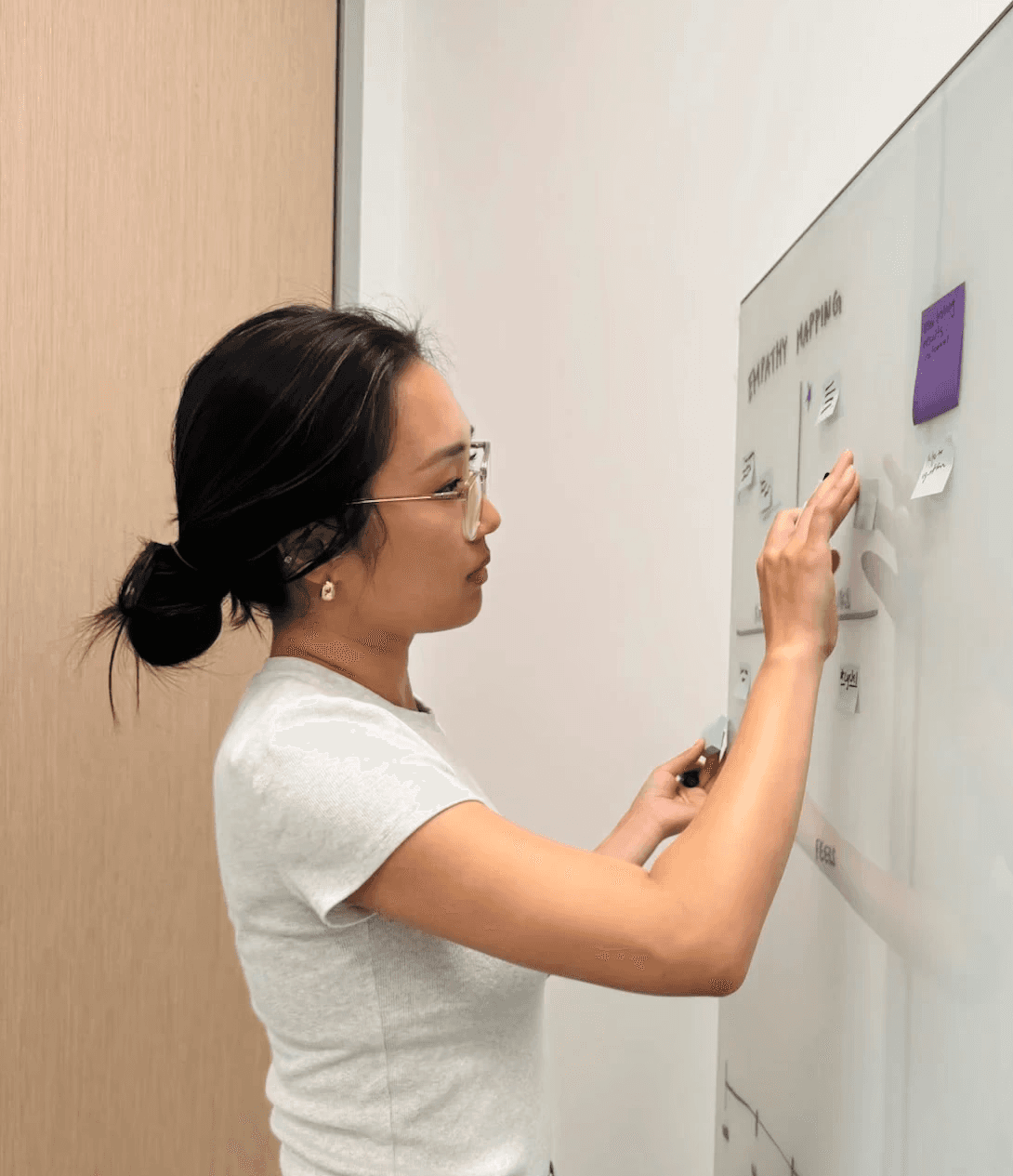 Bijou Kim, UX designer/researcher, working on a whiteboard.