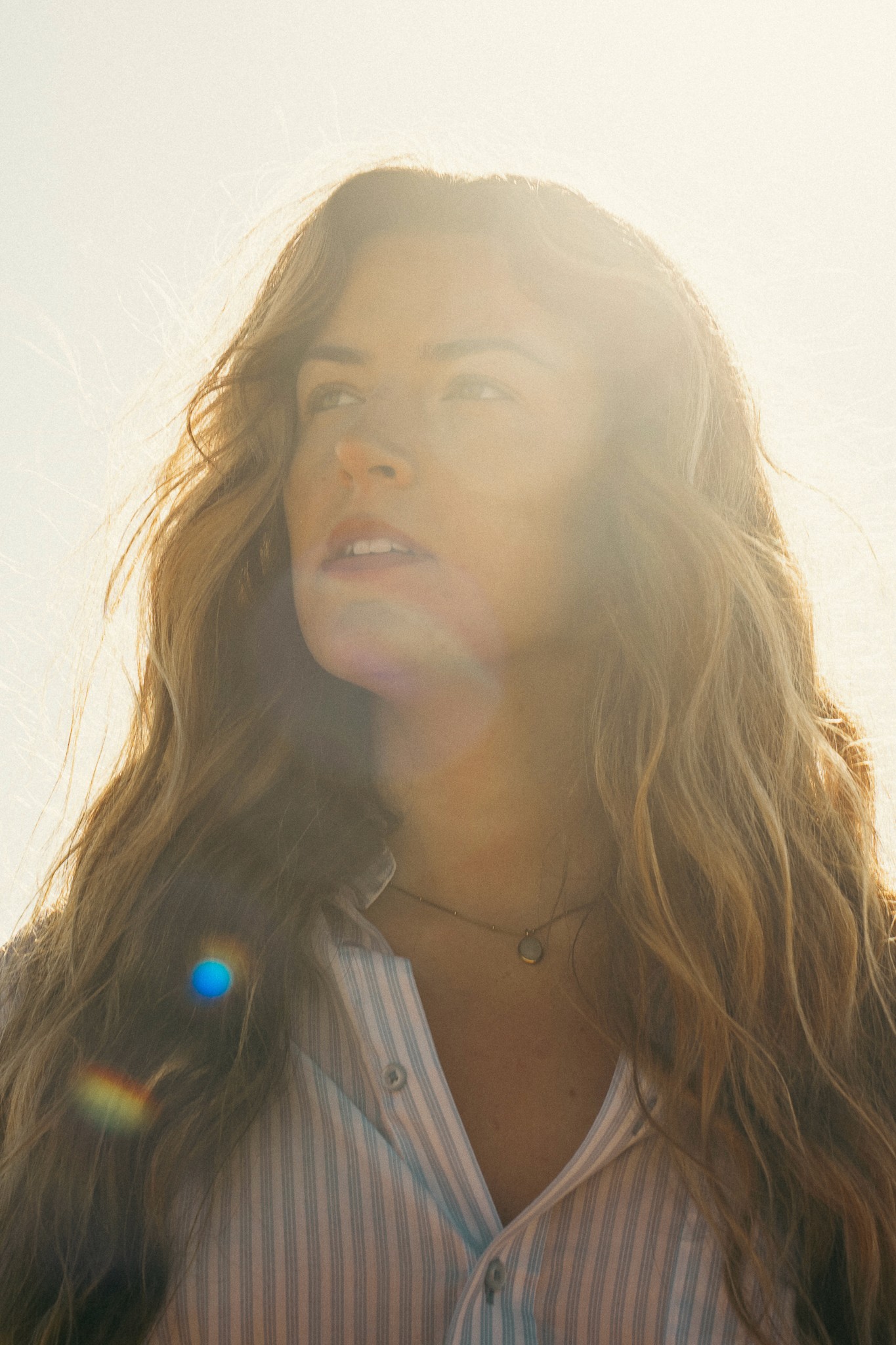 ortrait d’une femme regardant au loin à la plage au coucher du soleil, photographie de portrait par Robin Masson