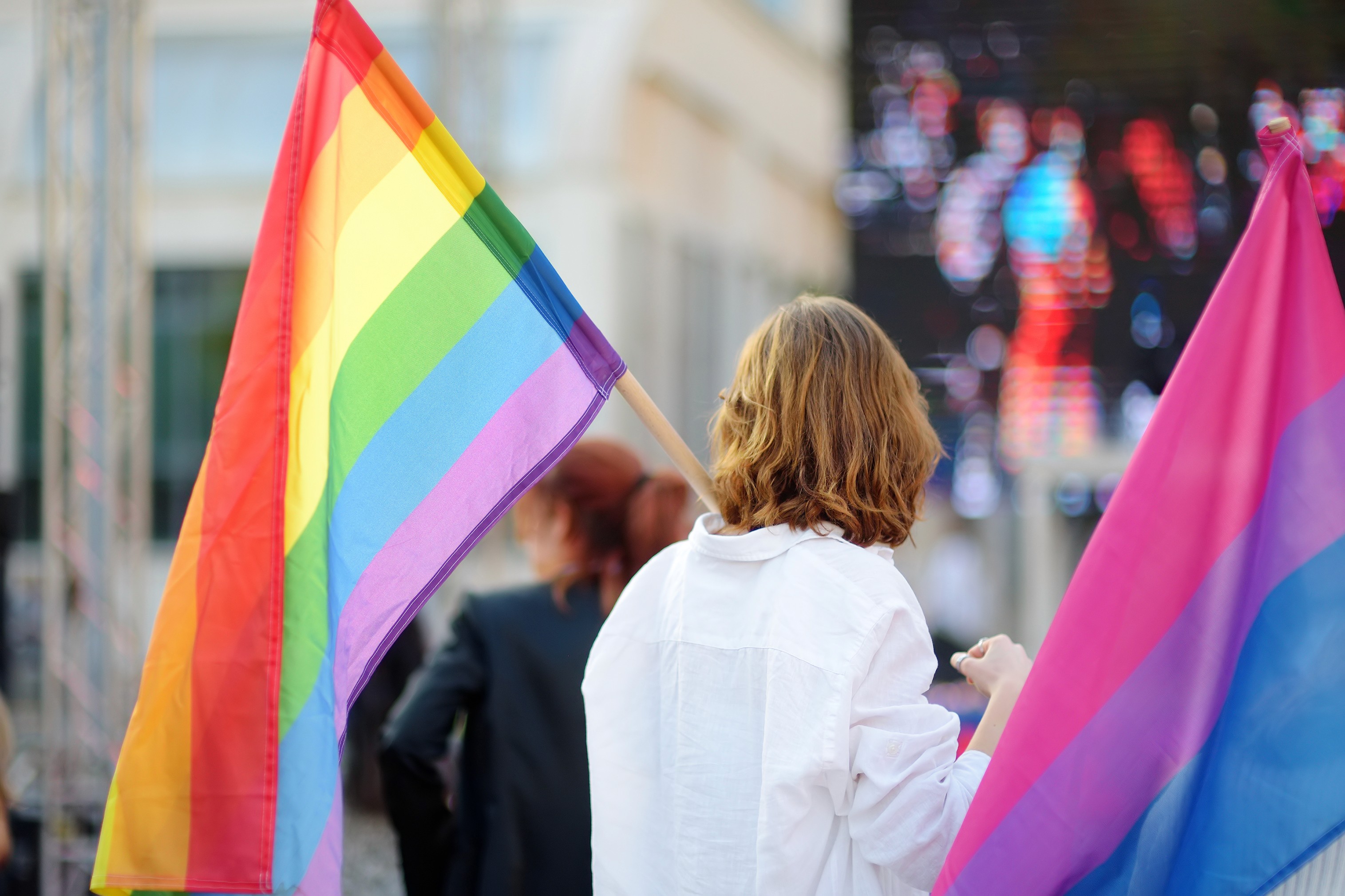 a person holding a rainbow pride flag.