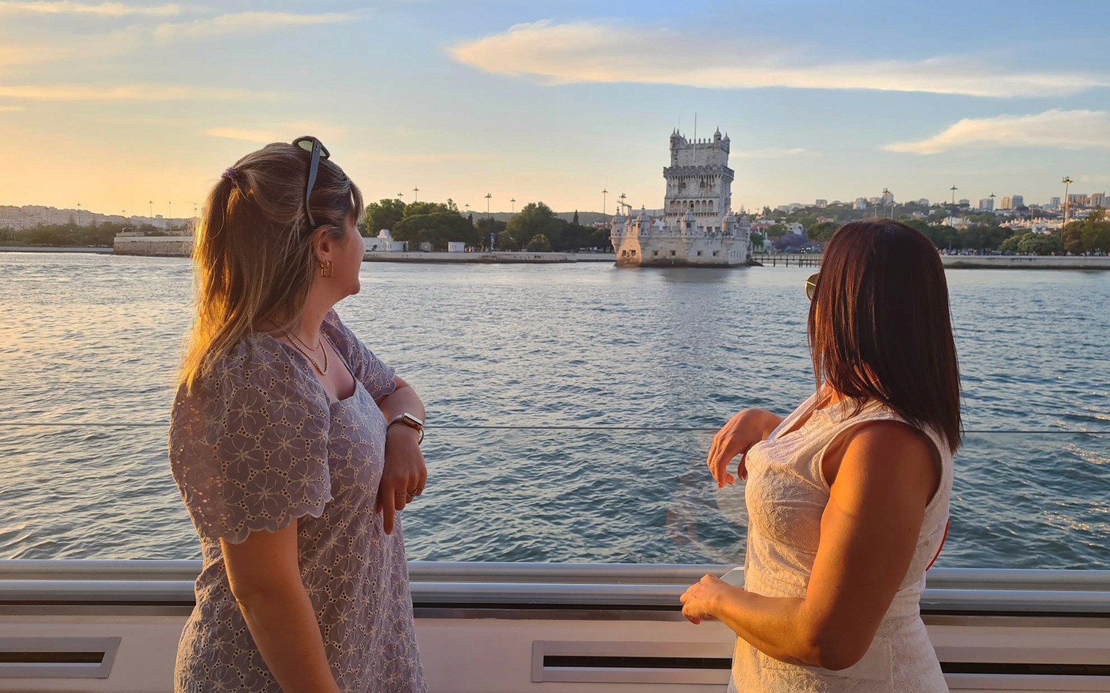 Two people enjoying a view of Belém Tower from a boat on the Tagus River.
