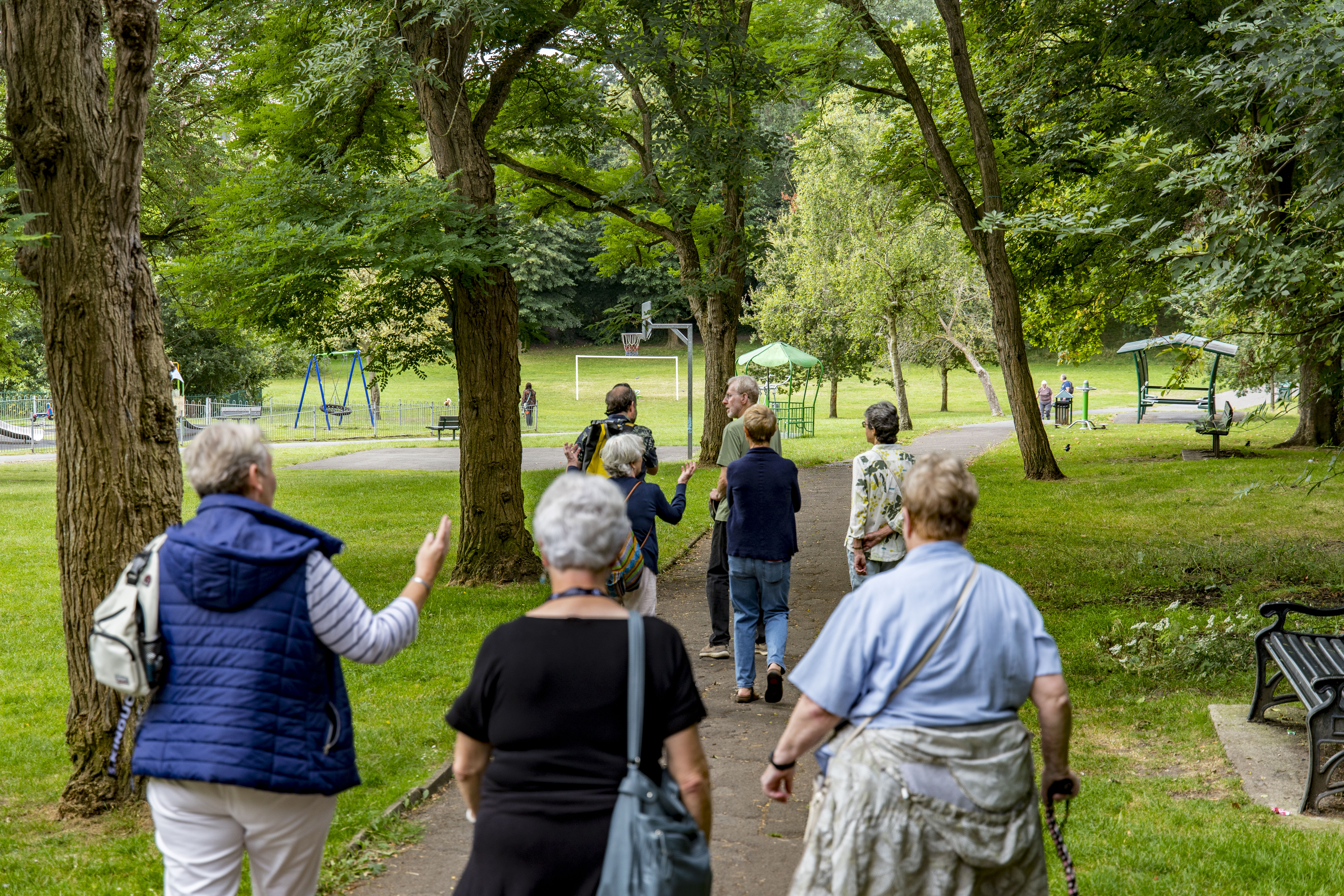 woman in black sleeveless dress standing under green tree during daytime