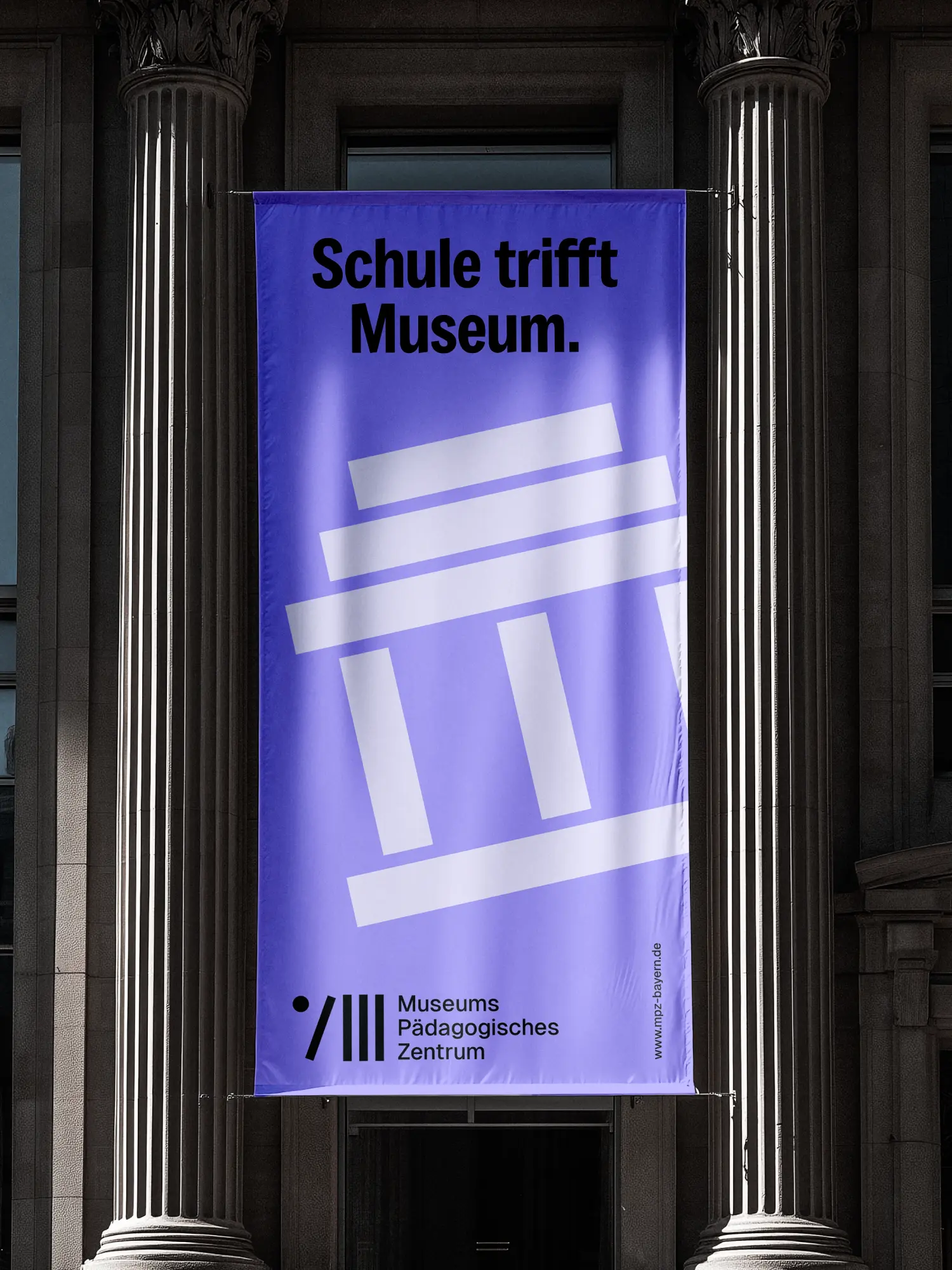 Lilafarbenes Banner „Schule trifft Museum“ zwischen klassischen Steinsäulen