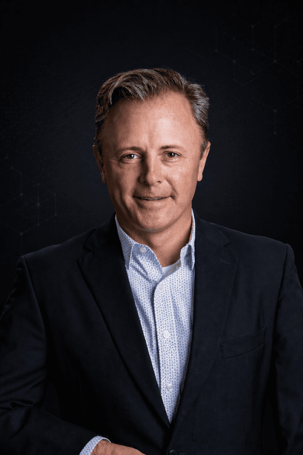 Professional portrait of a man in a dark suit against a black, softly lit background with subtle technology-inspired ambiance, matching a high-end enterprise website aesthetic.