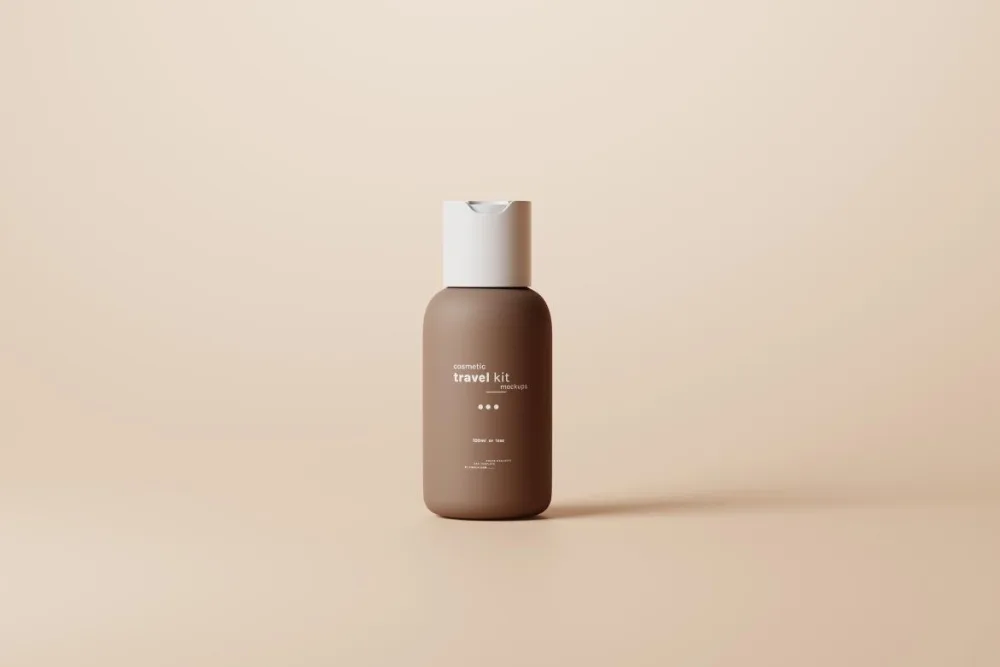A small, minimalist travel-sized cosmetic bottle with a matte brown finish and a white flip-top cap, standing upright on a beige background with soft lighting and subtle shadows.