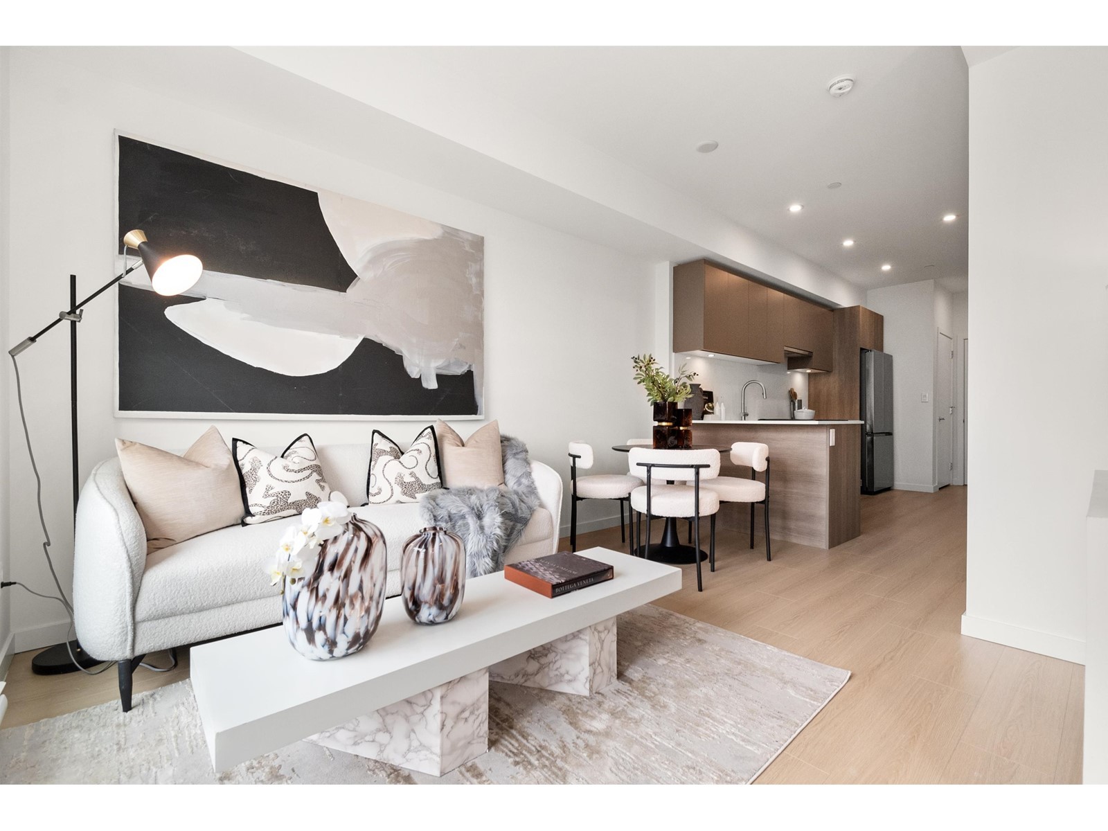 A modern living room with a white sofa, abstract wall art, and a stylish coffee table, featuring light wood flooring.