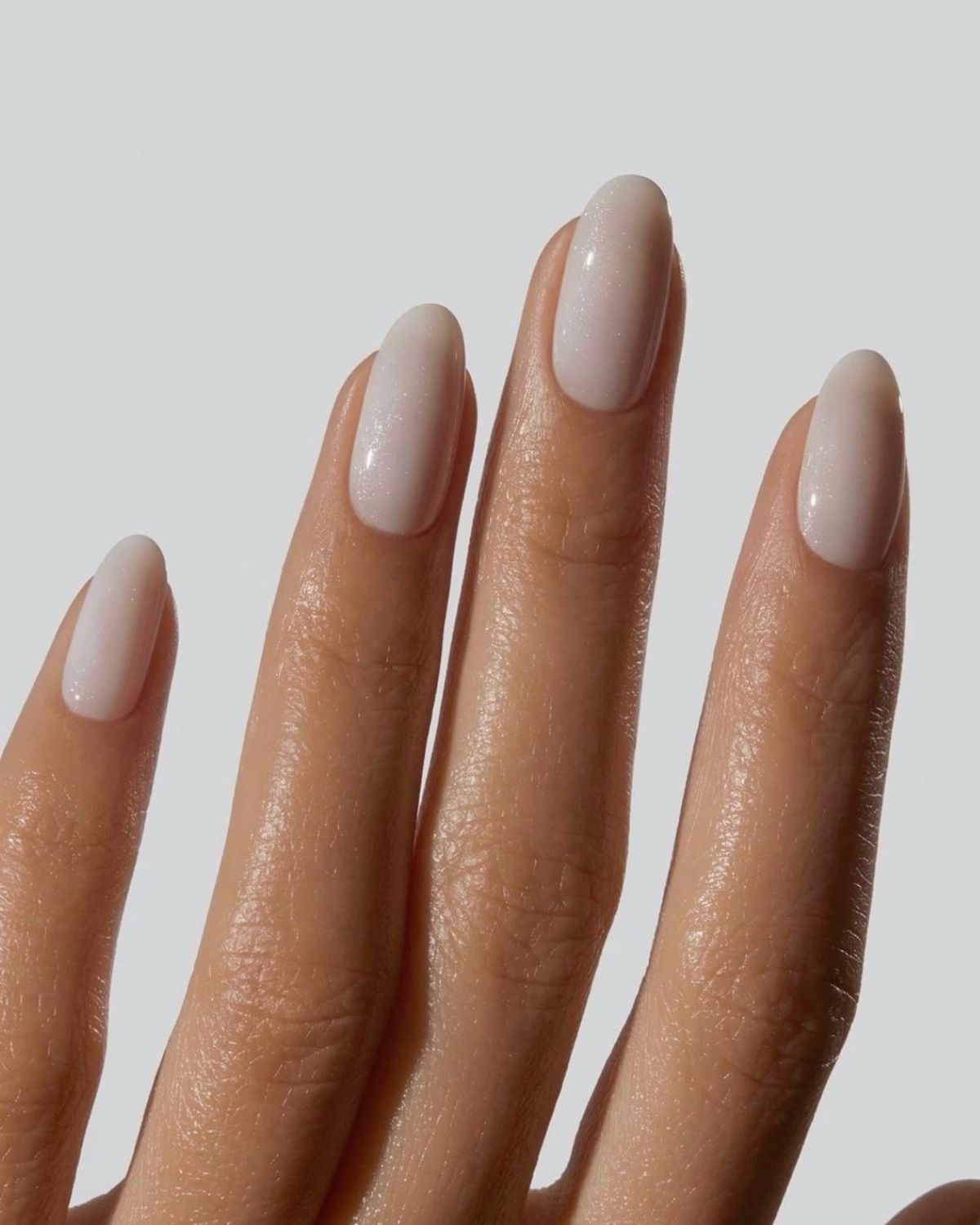 3D render of an abstract translucent glass sculpture with smooth, flowing organic curves floating against a minimal light gray background. The form resembles a fluid, molten loop with soft reflections and refractions