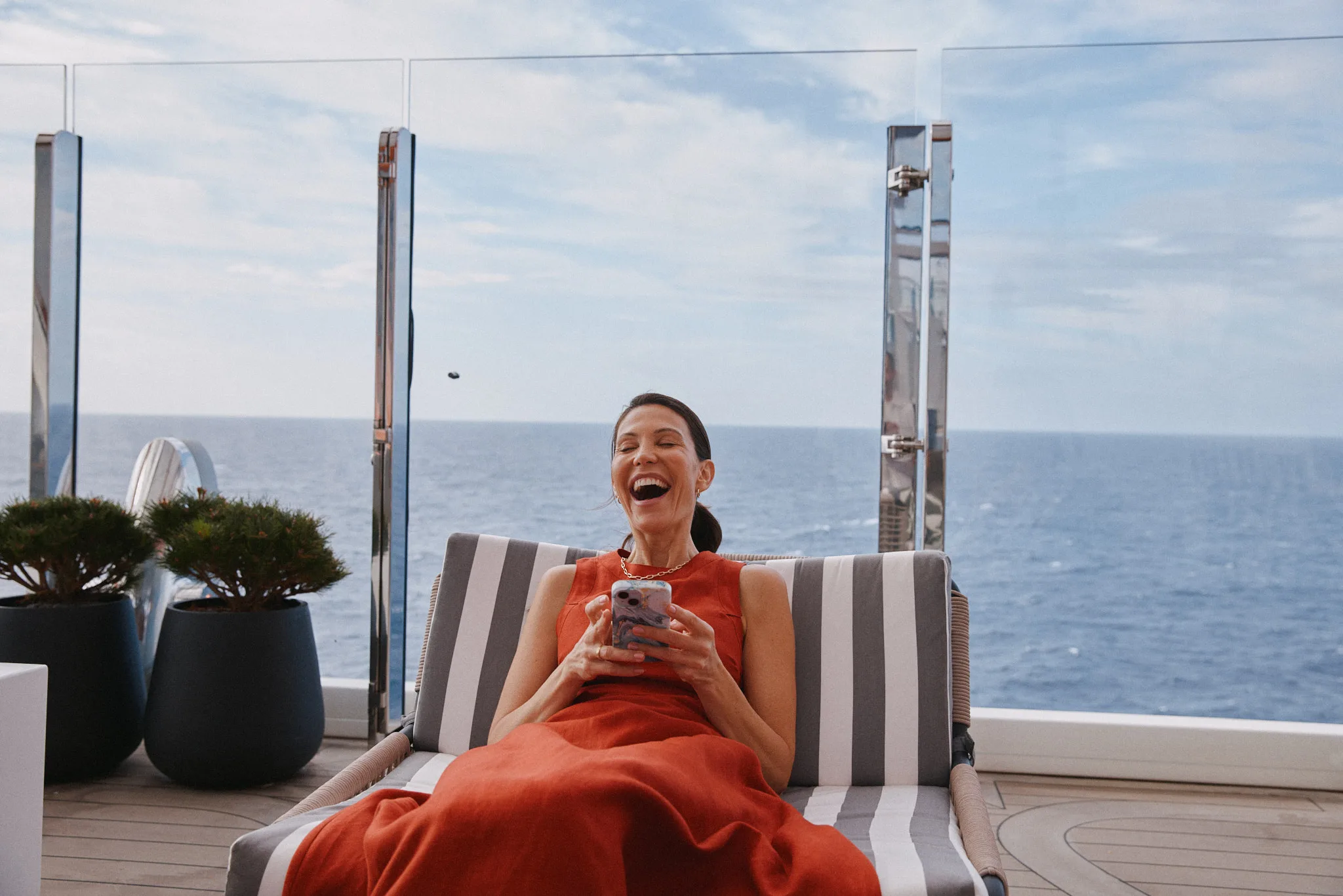 woman laughing over phone on ship deck — lifestyle photography by Tom Kubik