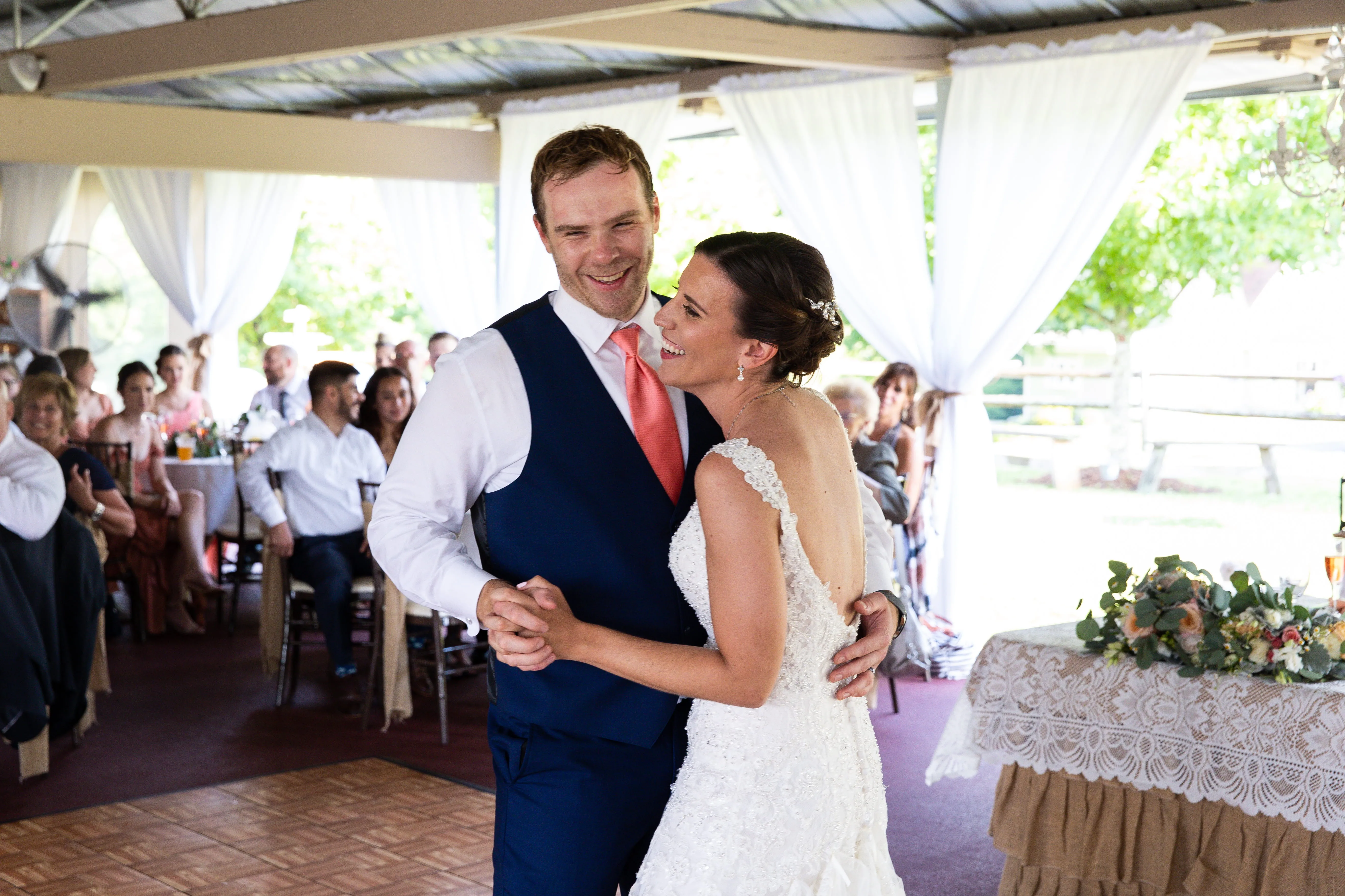 Bride and groom dancing during outdoor wedding reception under tent