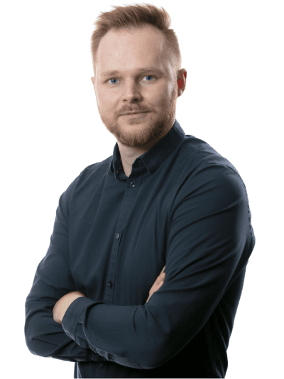 A confident person with short hair, wearing a dark sweater, stands with arms crossed, looking directly at the camera.