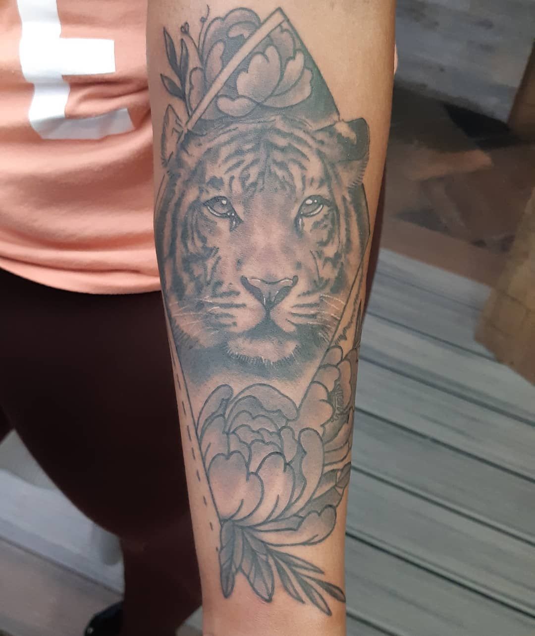 Black-and-grey tiger portrait tattoo on an upper arm