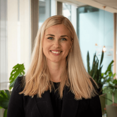 A young man with dark hair smiles at the camera, set against a modern indoor background.