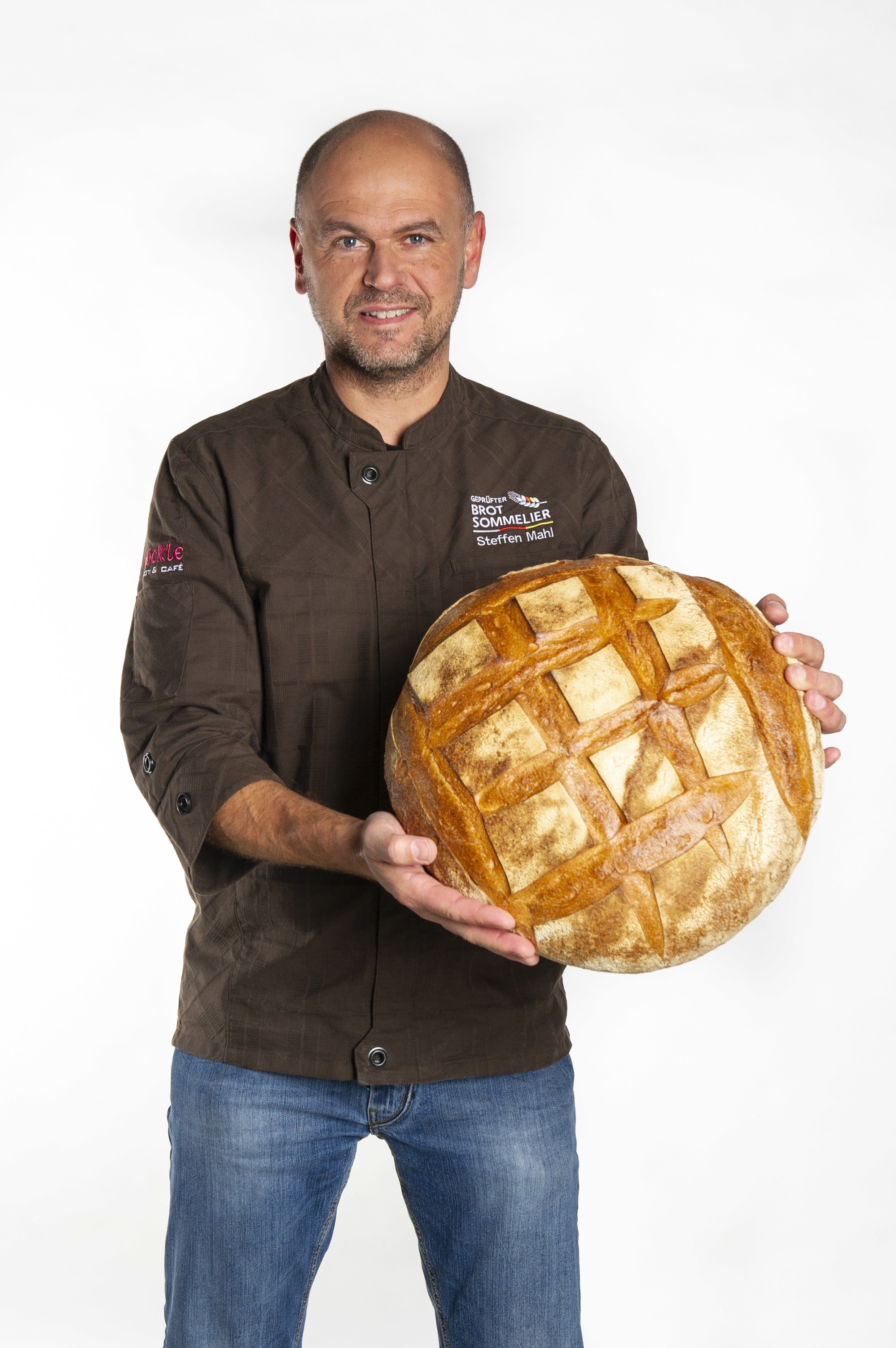 Steffen Mahl hält ein großes Brot vor einem weißen Hintergrund