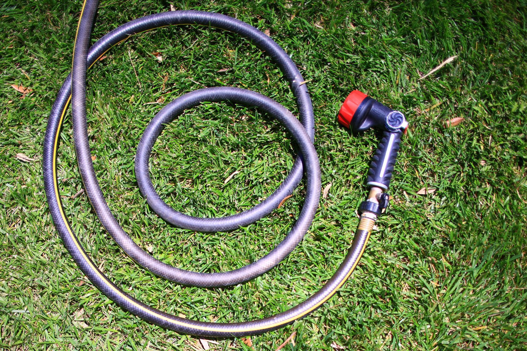 Garden hose with spray nozzle on green grass