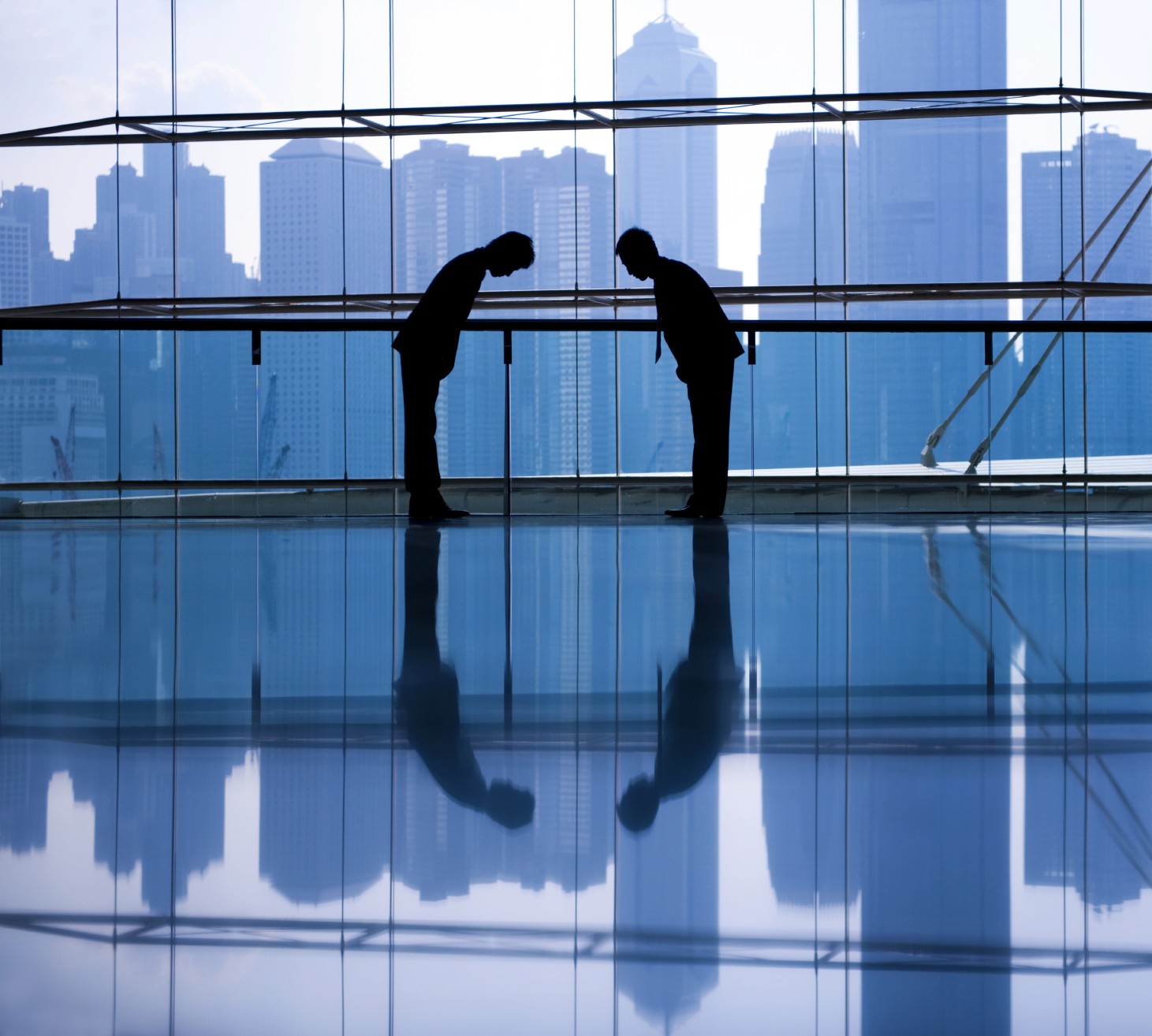 Two Asian men in business attire engaging in a respectful bowing gesture to each other, symbolizing mutual respect and strategic partnership in a professional setting. The body language reflects cultural norms of respect and collaboration, enhancing the dynamics of their strategic alliance. This image embodies the essence of cultural diversity, mutual understanding, and strength through collaboration in the business world, highlighting the power of strategic partnerships in driving meaningful learnings and growth.