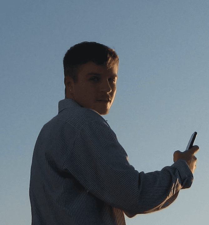 A thoughtful young person with dark hair gazes to the side, captured in soft black and white lighting.