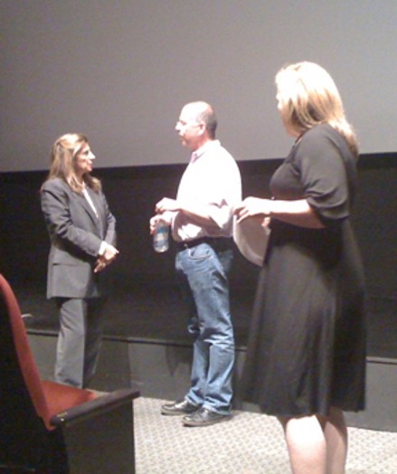 A photo of three persons talking on the stage.