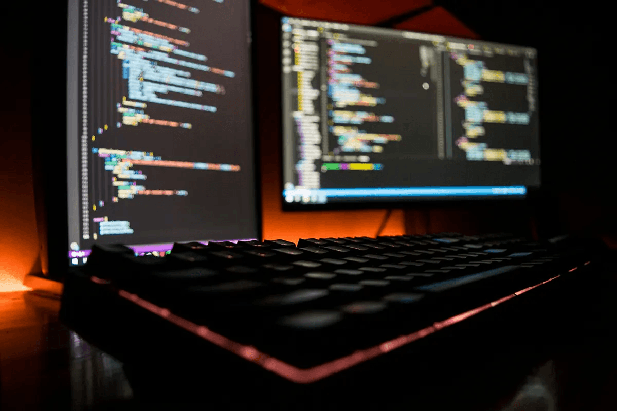 Desktop computer displaying code on screen with red LED lighting in the background