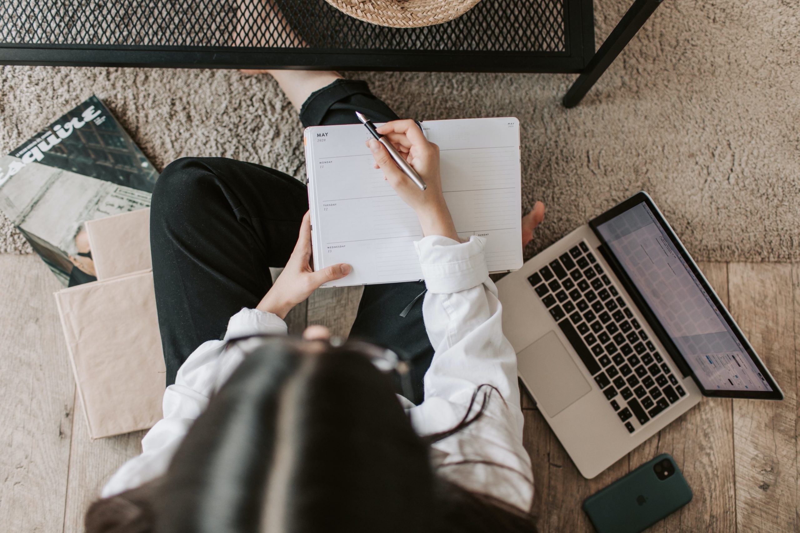 girl self-learning on floor with planner on laptop and laptop next to her