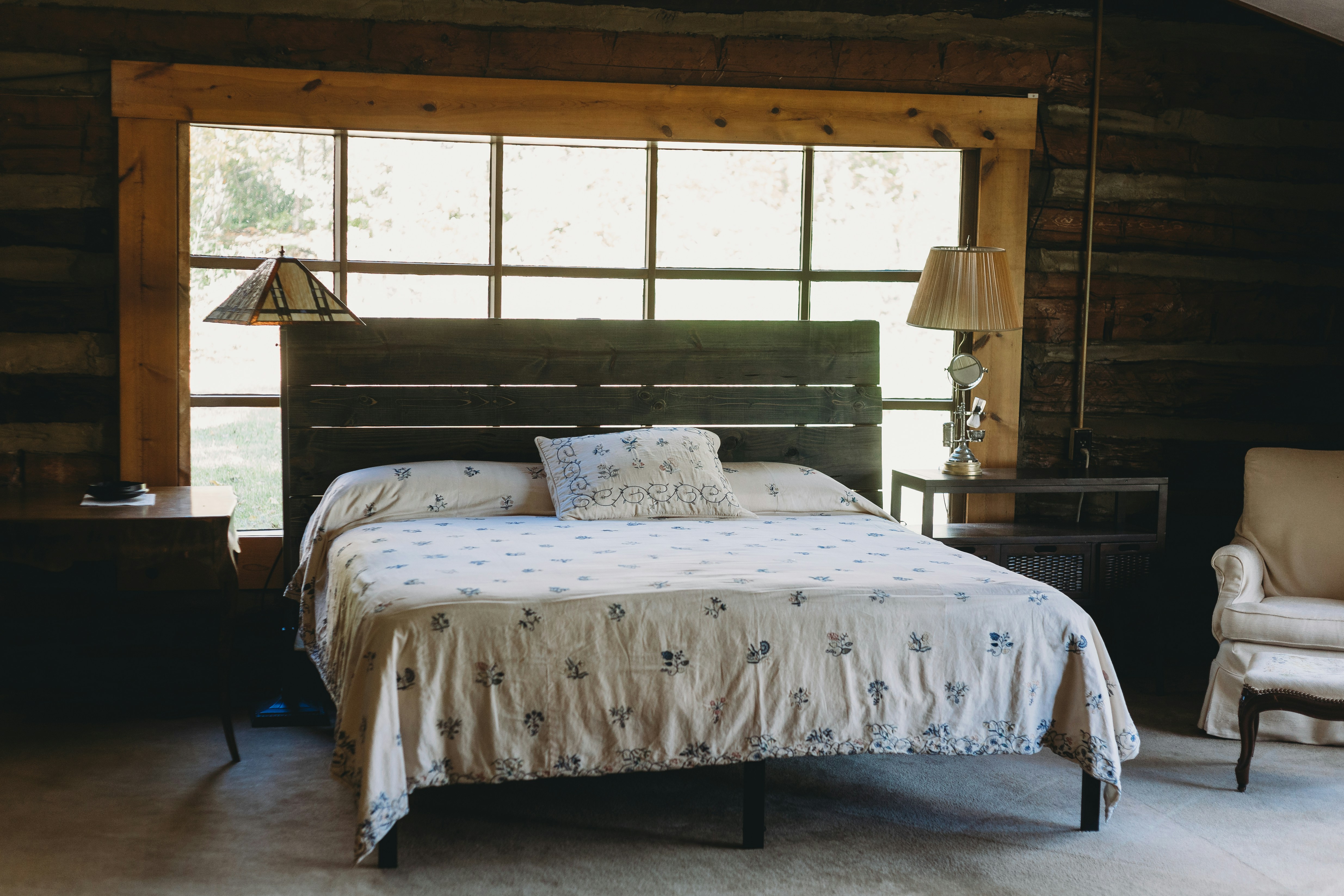 A bedroom with a wooden headboard and a big window