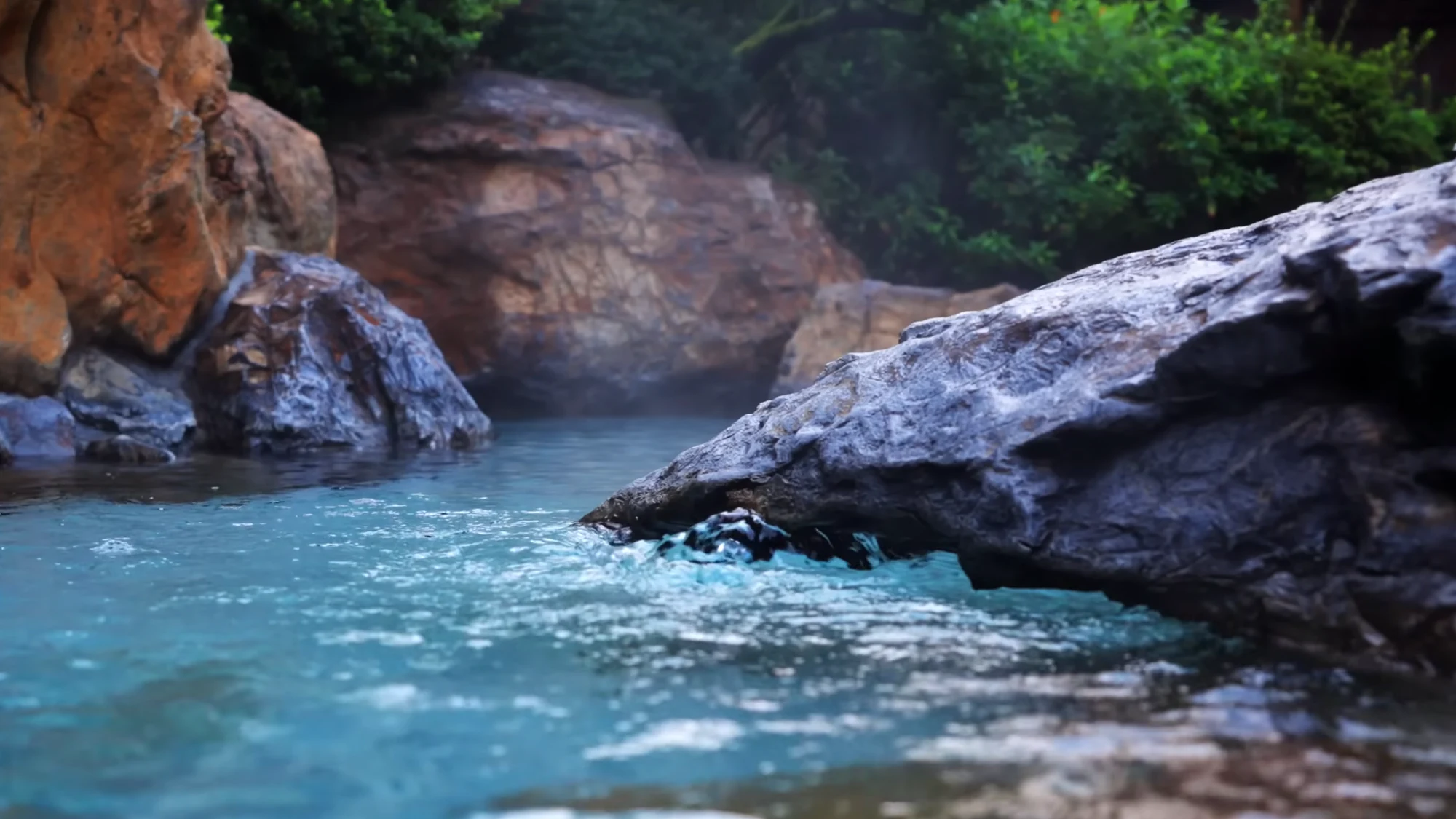Turquoise water moving between boulders in a river gorge near Kinosaki.