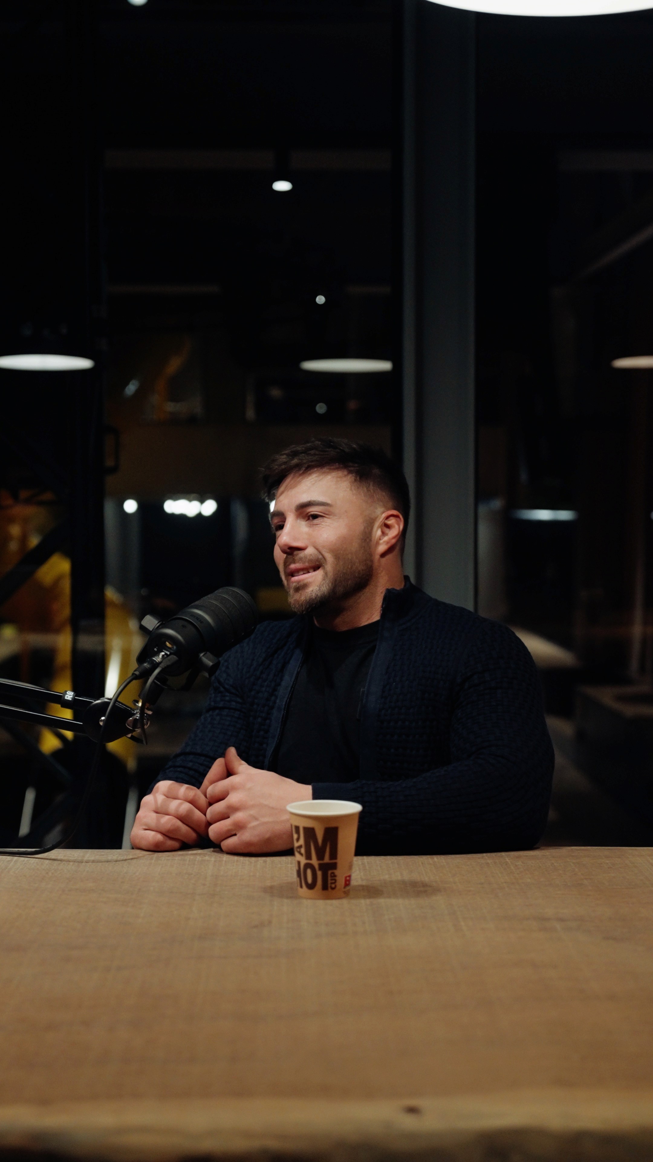 Elton Berisha deelt zijn levensverhaal tijdens het interview en spreekt openhartig met de interviewers, terwijl een microfoon in beeld is.