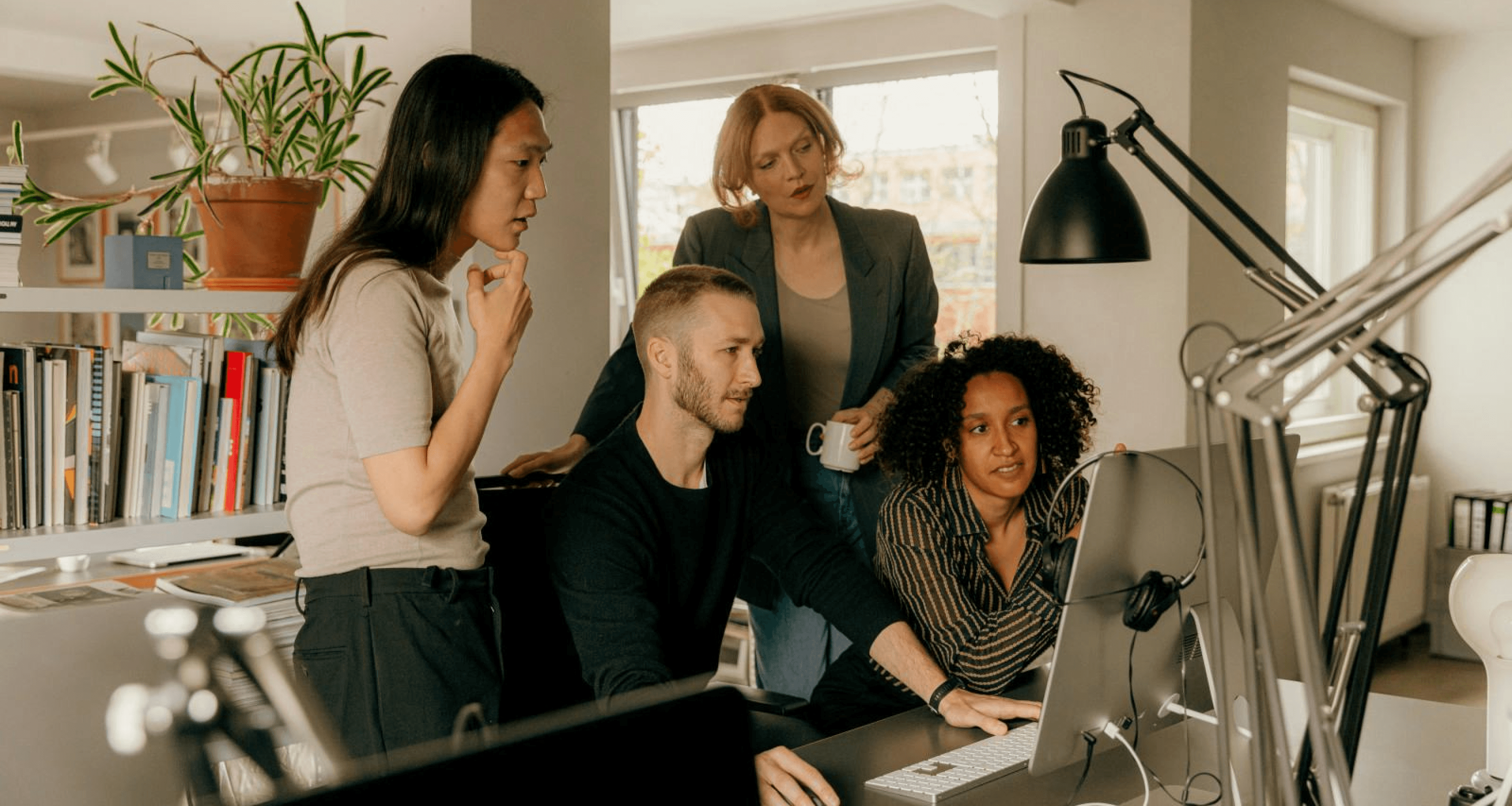 A group of professionals working together at a computer, discussing and brainstorming ideas collaboratively.