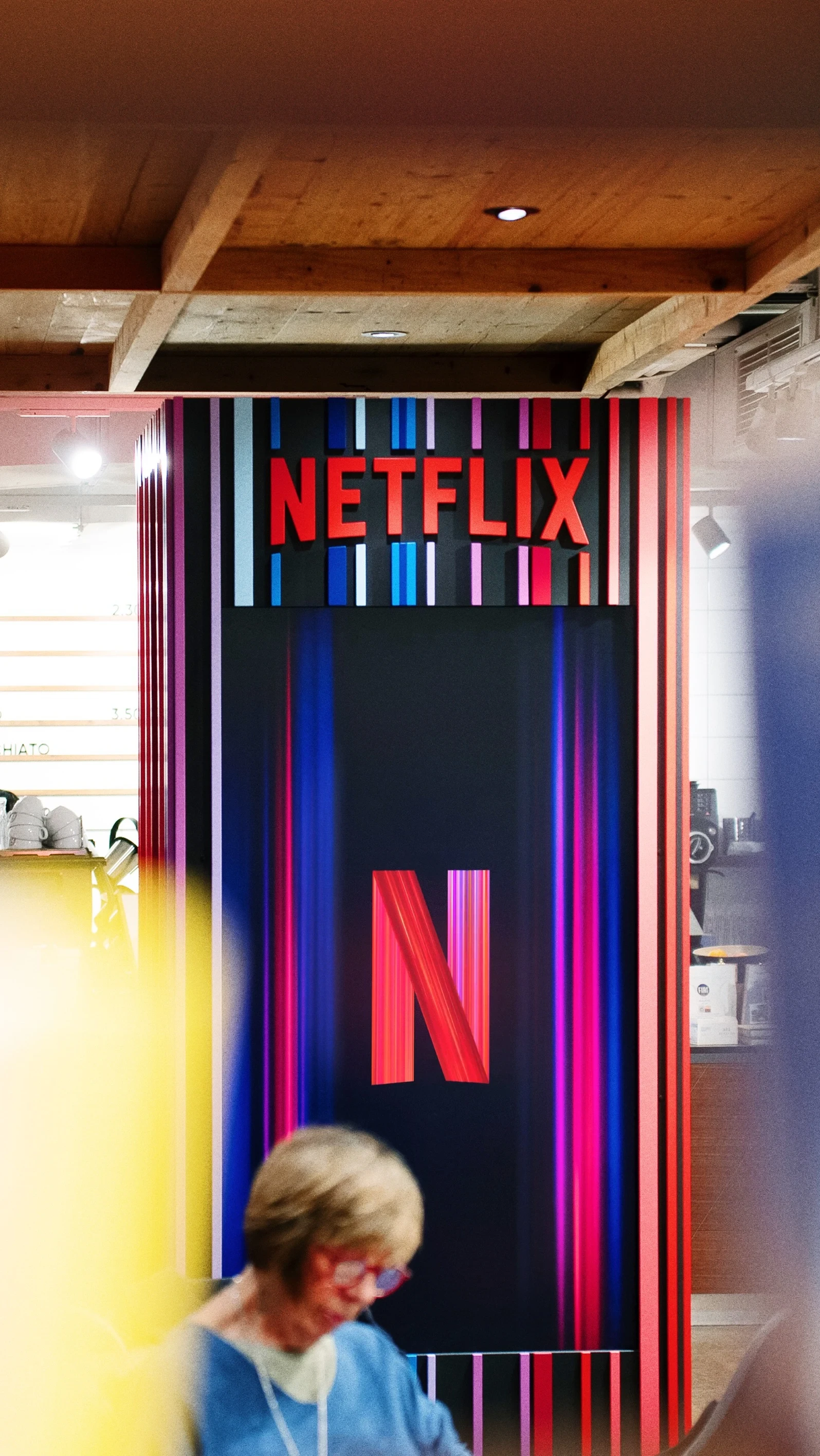 Front of the NETFLIX TOWER in a bookstore with red Netflix lettering, large N logo and vertical light streaks in red, blue and purple.