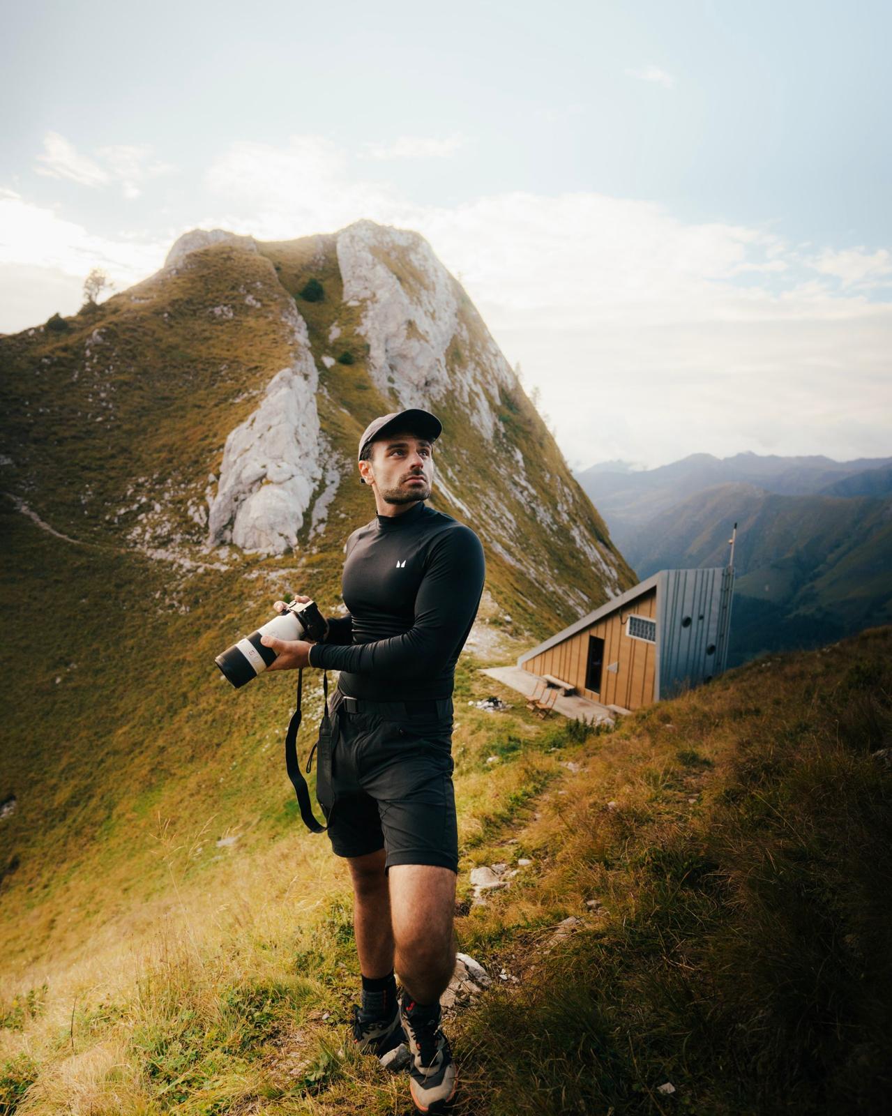 A person holding a camera is silhouetted against vivid orange stage lights. The scene conveys focus and creativity with a dramatic, moody atmosphere.