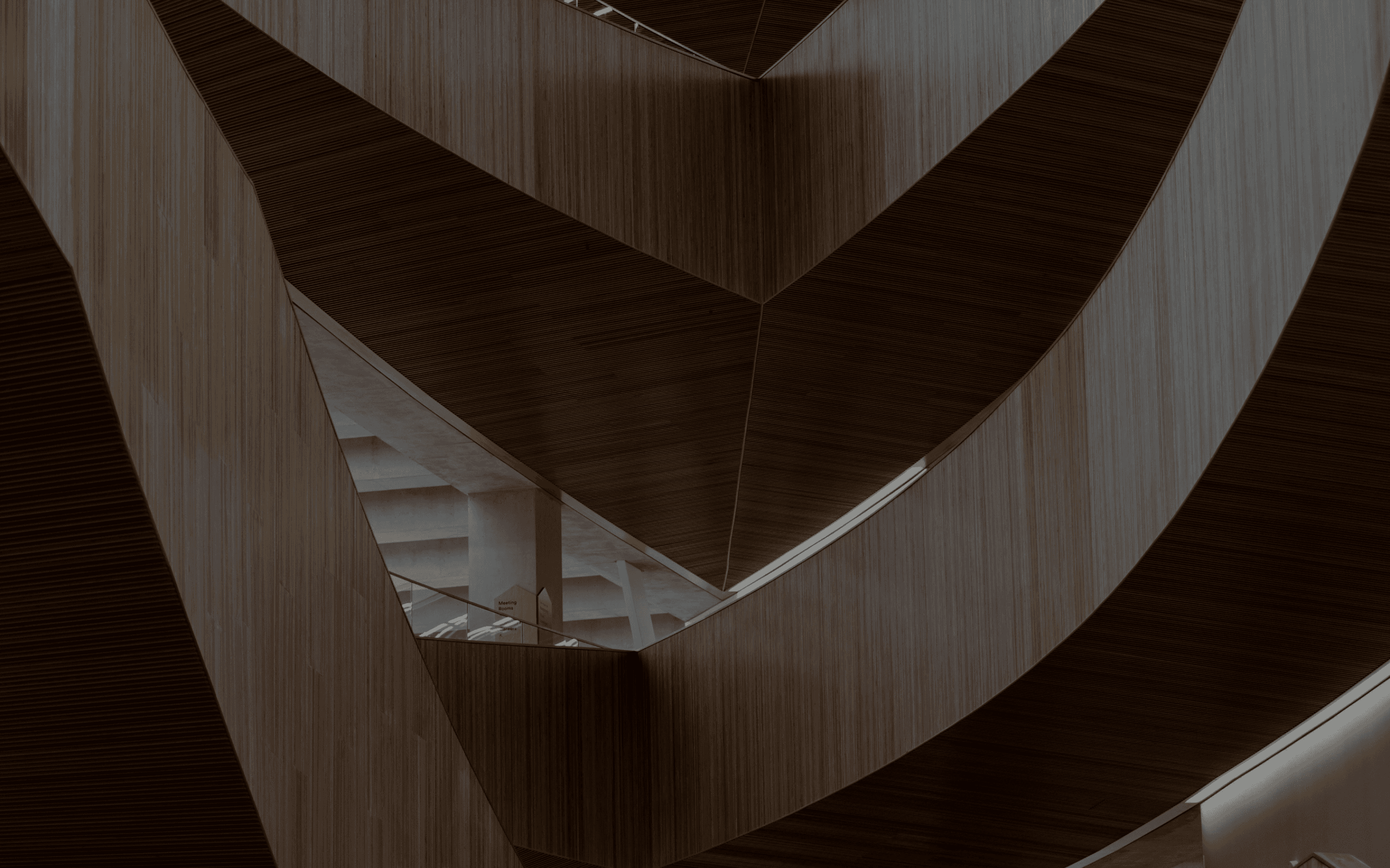 Abstract architectural view of dark wooden panels with sharp geometric angles and curves in a moody interior.