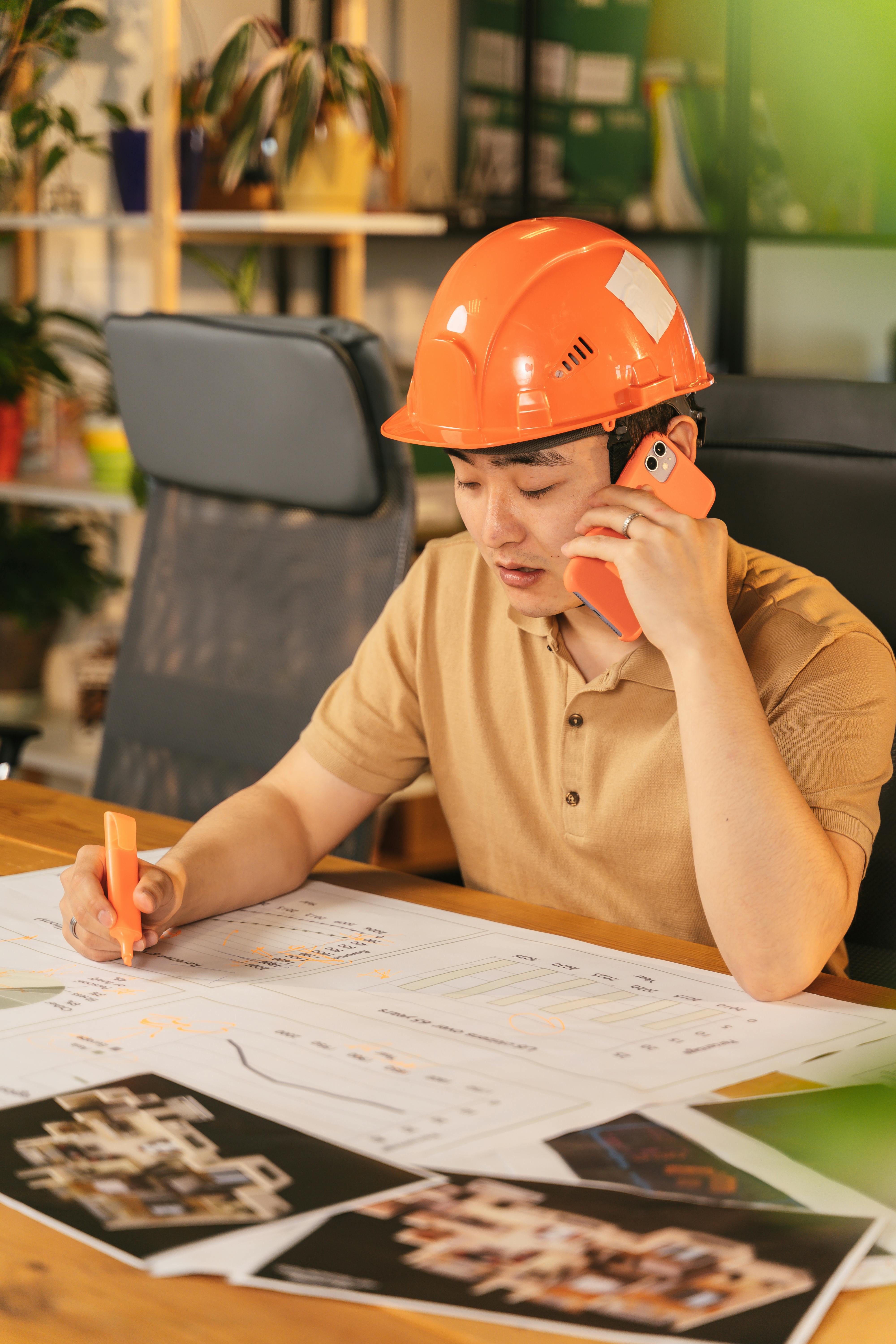 asian-male-architect-reviewing-blueprints-and-talking-on-phone-indoors,-wearing- - antoni-shkraba-production (pexels)