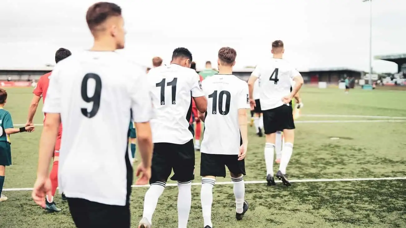 Young footballers in Bavaria march onto the pitch together, representative of the cohesion and growth in amateur football, supported by the Bavarian Football Association.