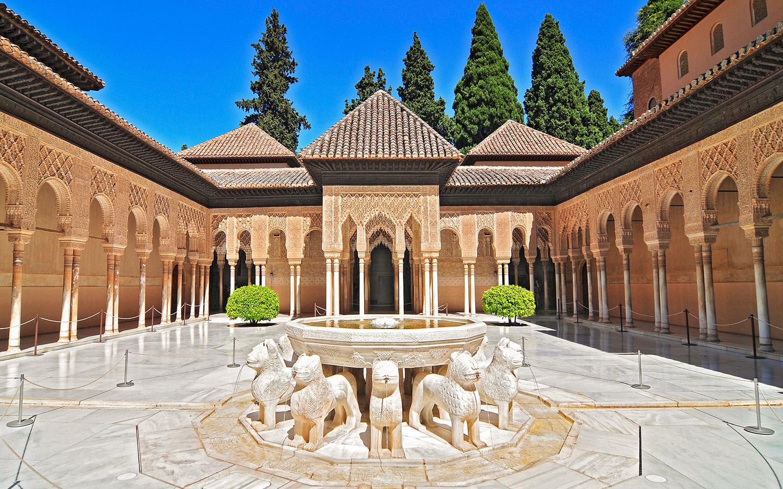 Cortile dei Leoni all'Alhambra di Granada, con archi decorati e fontana dei leoni.