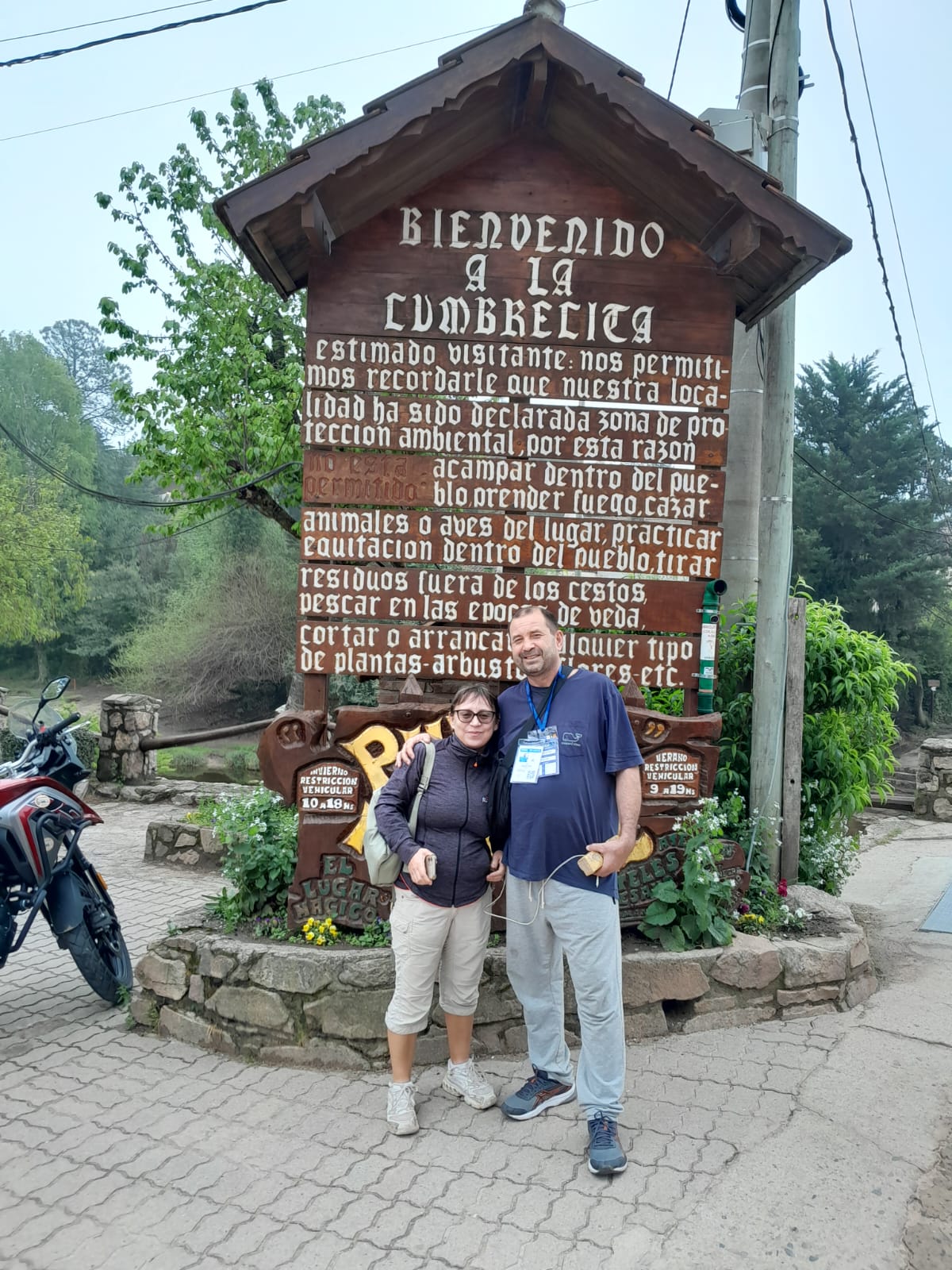 Mujer sentada sobre un tronco frente a una cascada doble en un bosque frondoso de Argentina.