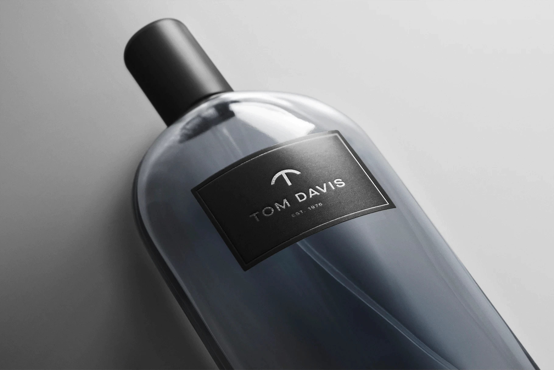 Fragrance bottle mockup containing a deep blue or grey colored liquid.