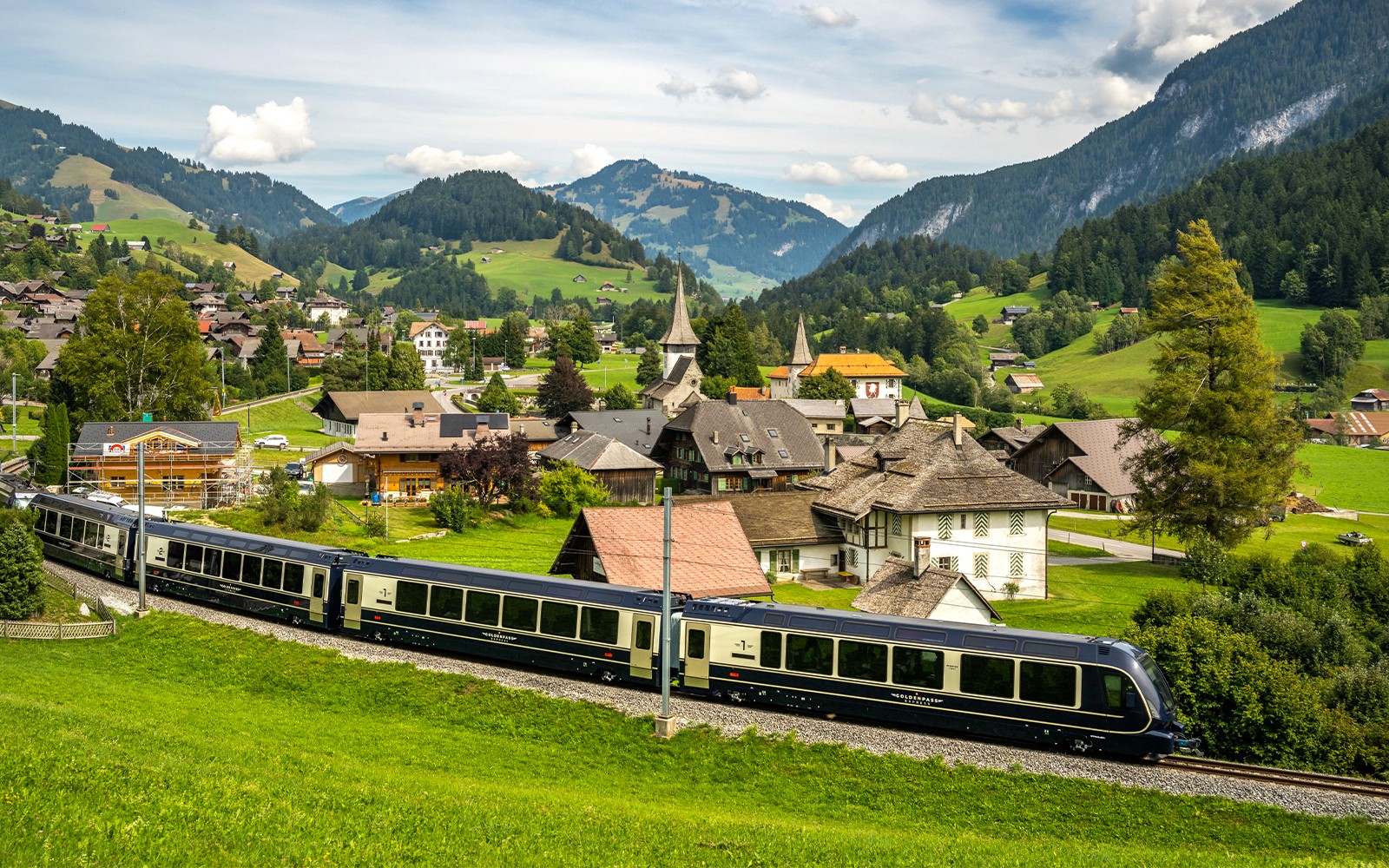 Scenic view of the GoldenPass Express train passing through a Swiss village near Interlaken and Gstaad.