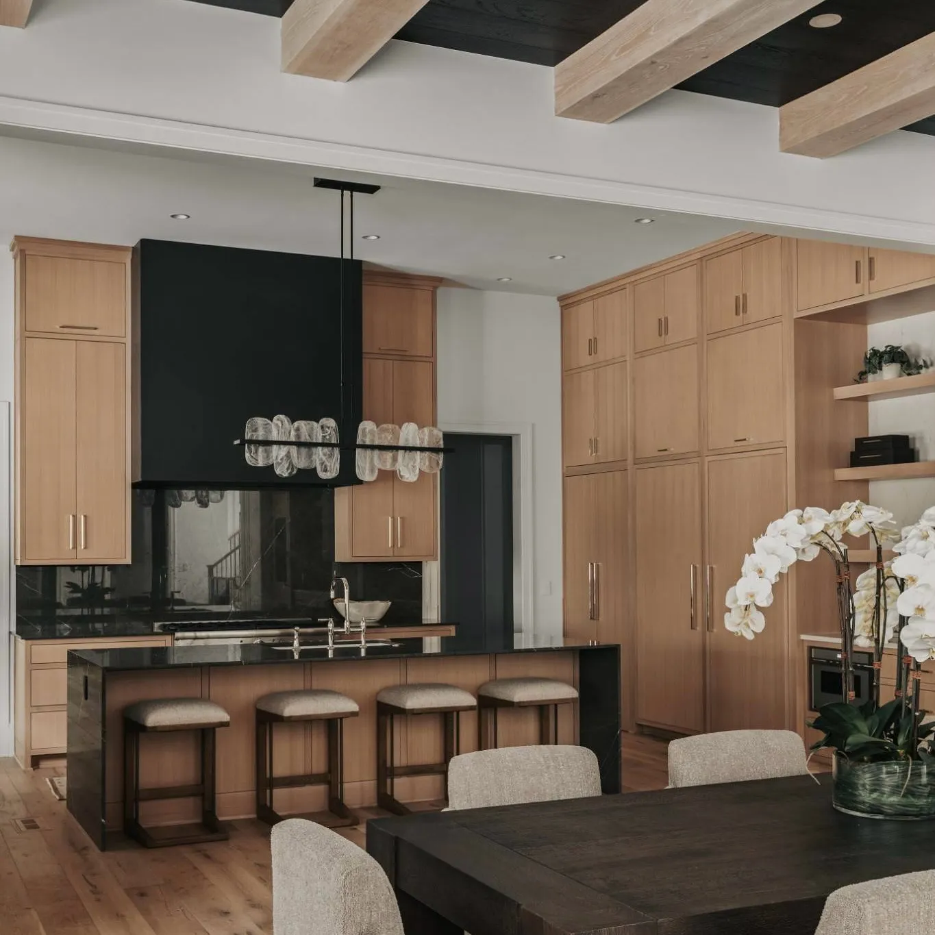 A modern kitchen with dark cabinets, an island, and white flowers.