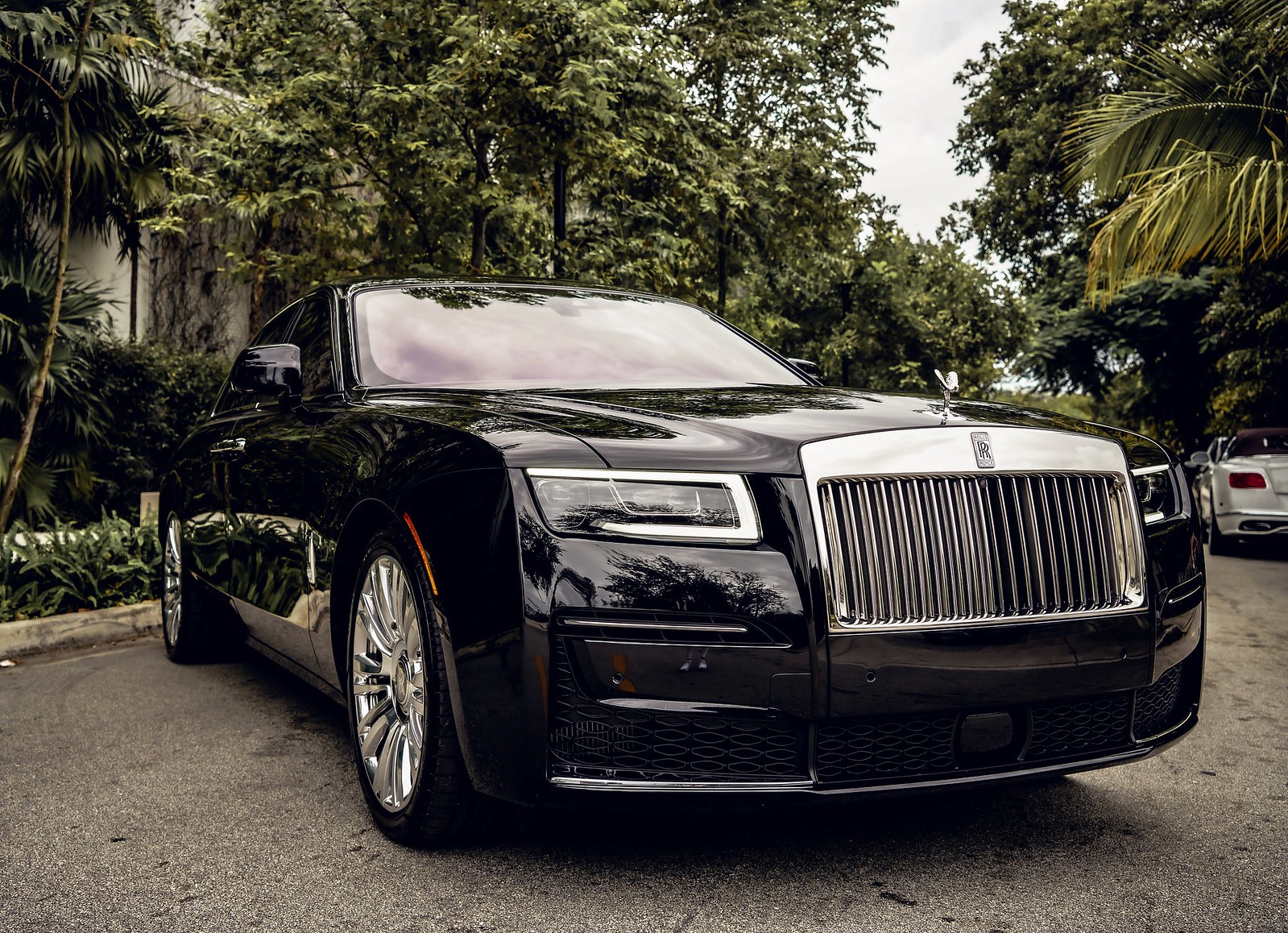 A sleek, black Rolls-Royce Ghost showcasing its bold grille and distinctive headlights from an angled front view.