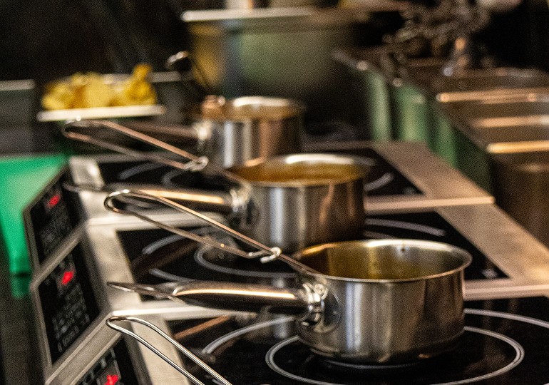 Profesionální kuchyně s nerezovými hrnci na sporáku