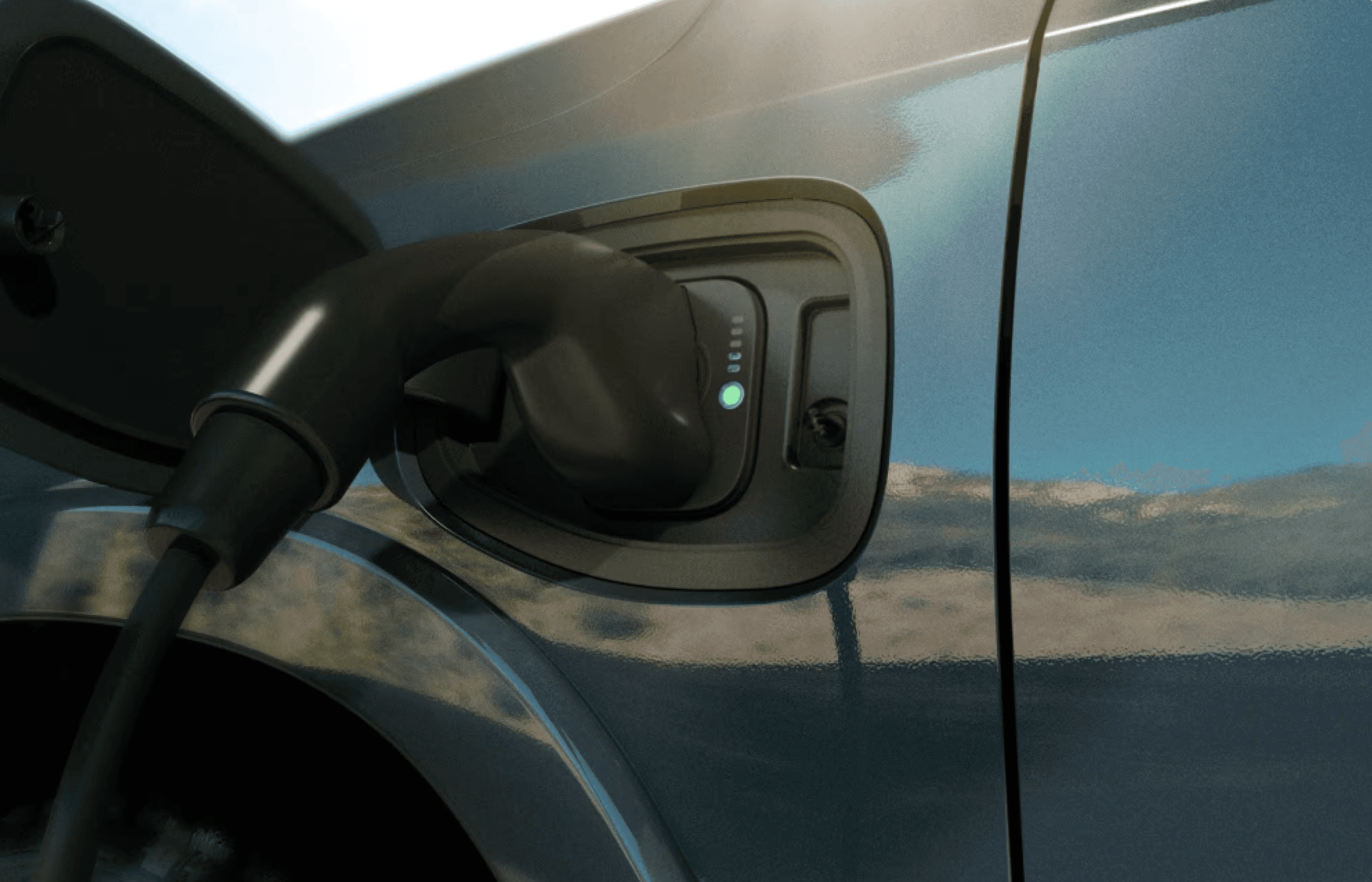 A close-up of the RAM 1500 REV charging port with a cable plugged in and the indicator light glowing green.