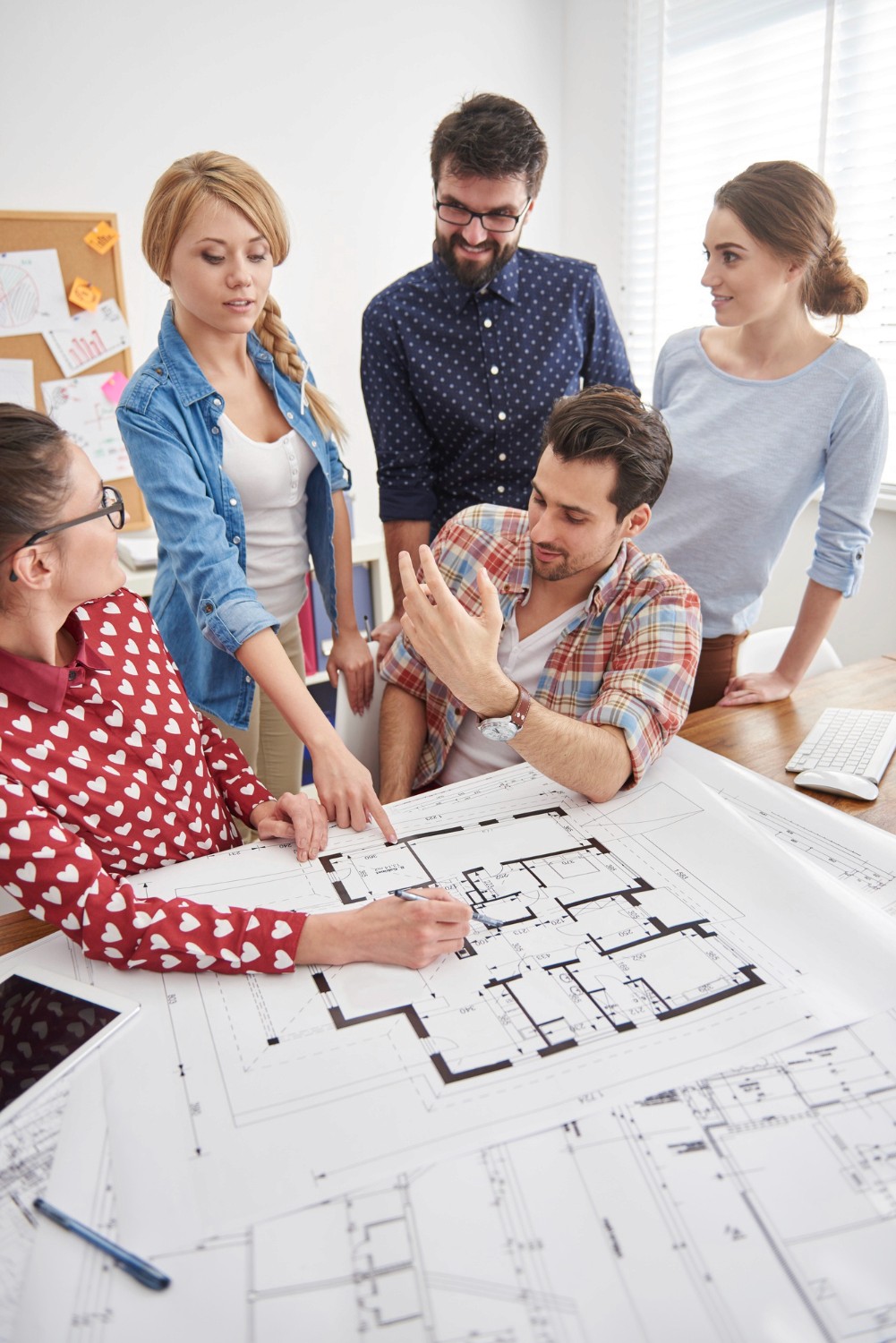 機場藝廊設計師團隊進行展覽策劃討論，桌上擺放建築比例模型與空間佈置平面圖。