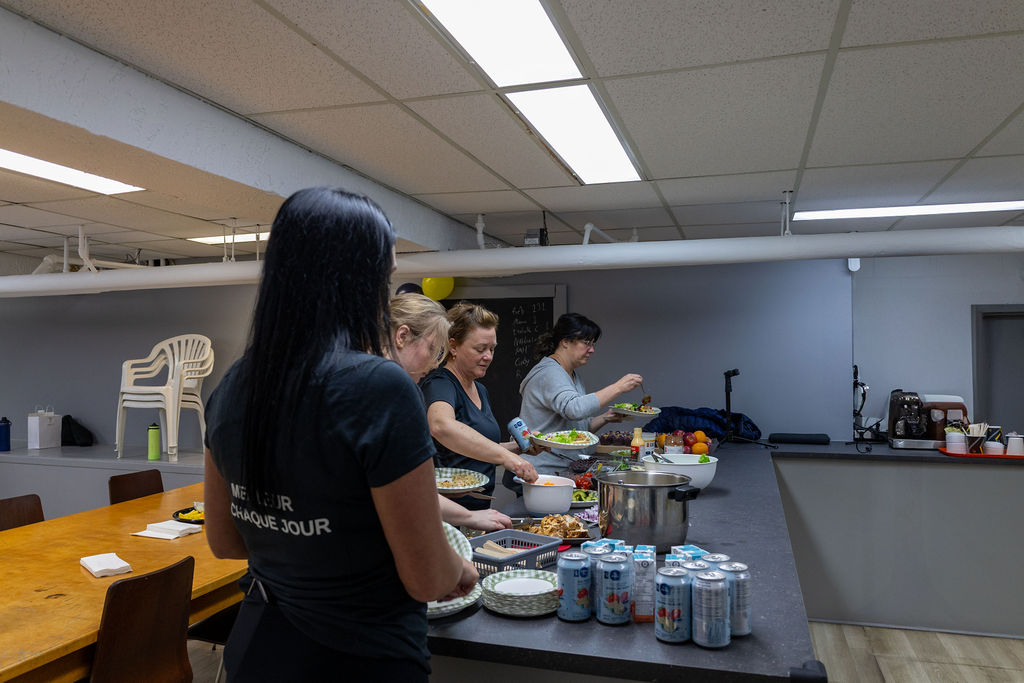Femme portant un chandail Progrès-Fit lors d'un événement communautaire autour d'un buffet santé nutritif.
