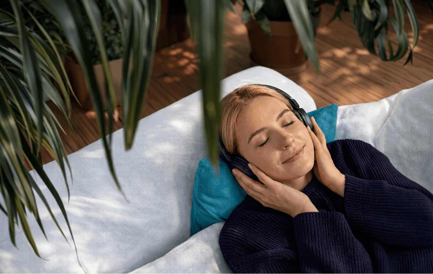 Lady laying down under the Sun, wearing headphones and enjoying Clarity's focus mode.
