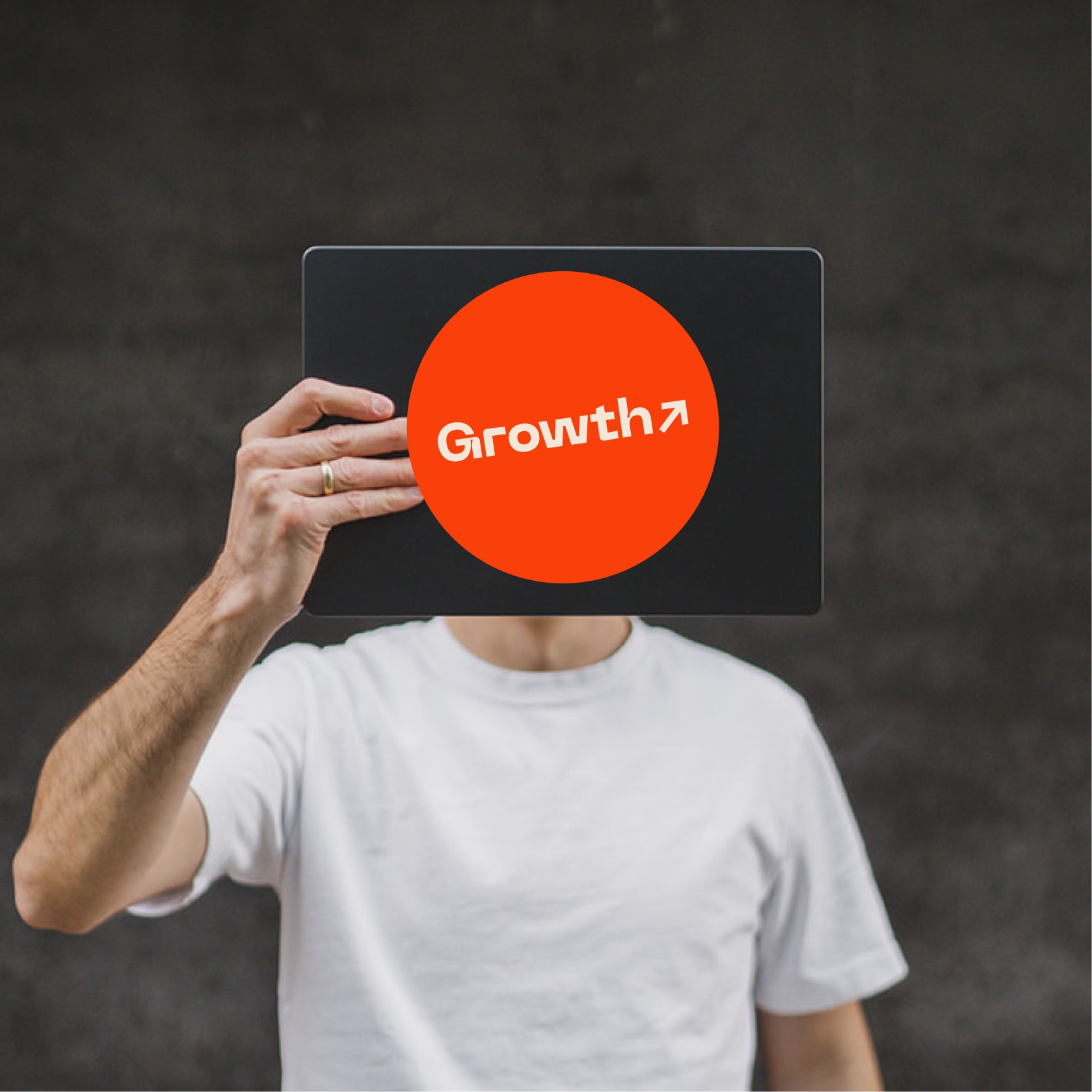 Julian holding a macbook with a giant sticker that says Growth in front of his face