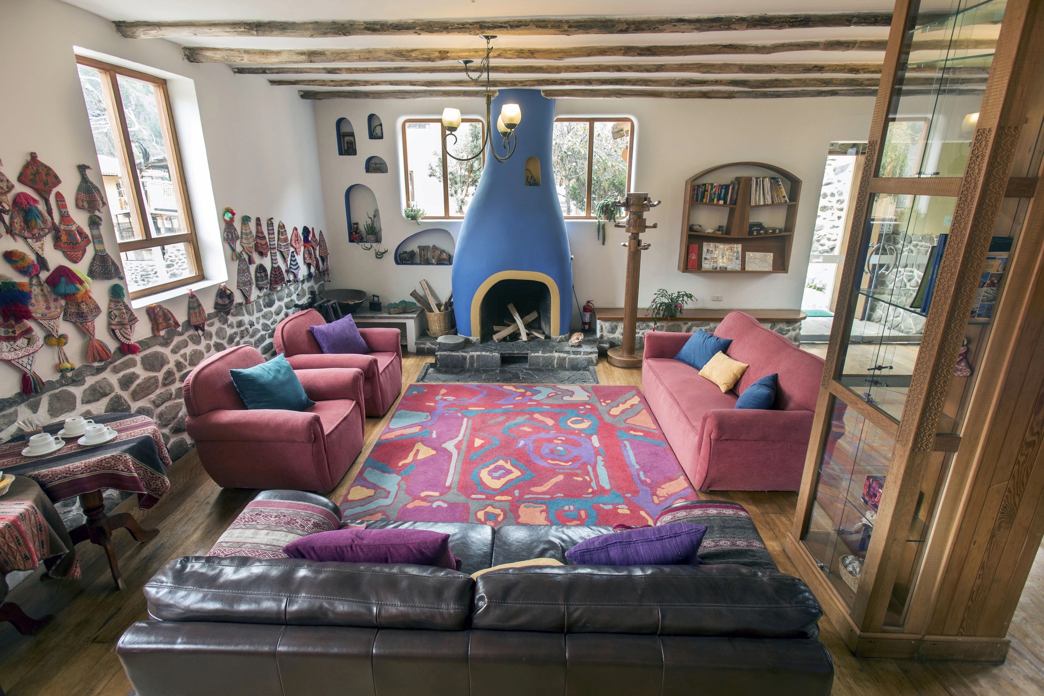 Spacious lounge with red armchairs, a patterned rug, and a blue sculpted fireplace.
