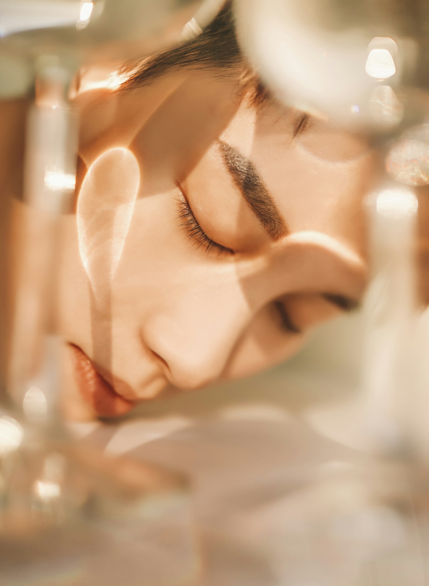 Woman with her eyes closed in warm light, seen through soft glass reflections