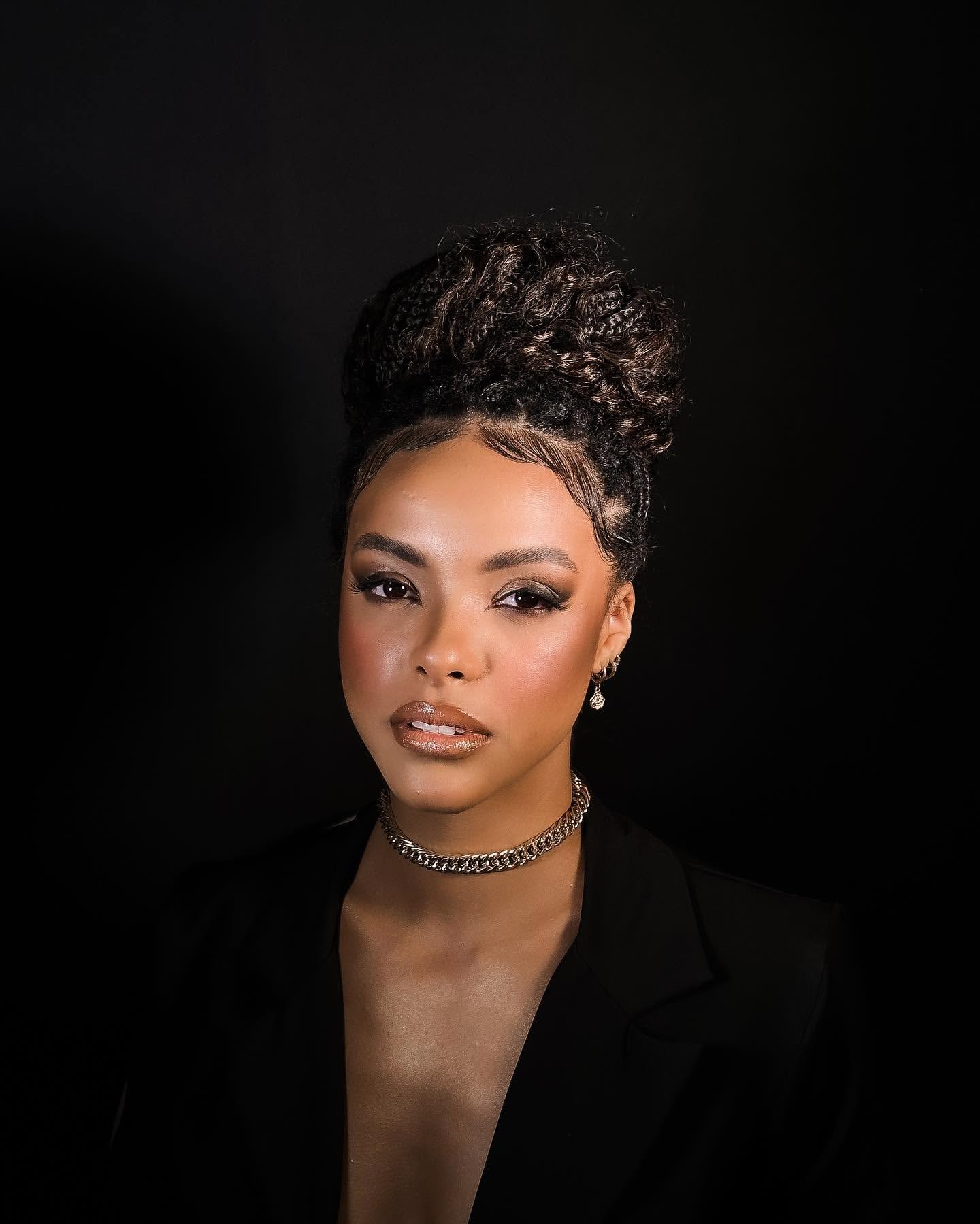 Modelo maquiada por Pry Sanches Beauty com um visual marcante e sofisticado. A especialista em maquiagem e design de cílios destacou a pele com um contorno preciso, olhos com sombra suave e lábios em tom nude. O penteado alto e elegante, combinado com o colar de corrente, cria um look poderoso, ideal para eventos de gala e editoriais de moda. Técnica de maquiagem para pele negra com acabamento impecável.
