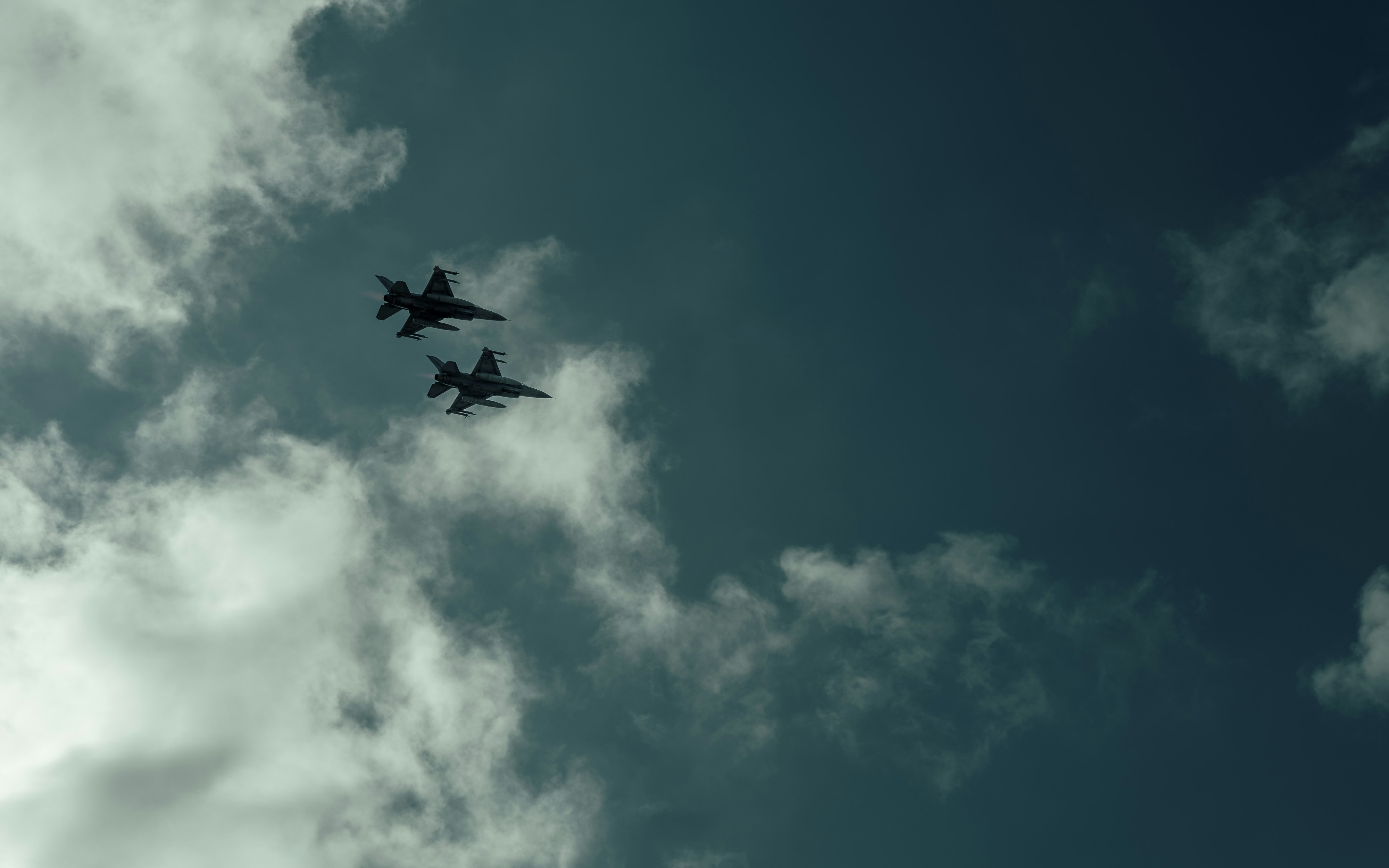 A couple of planes flying through a cloudy sky